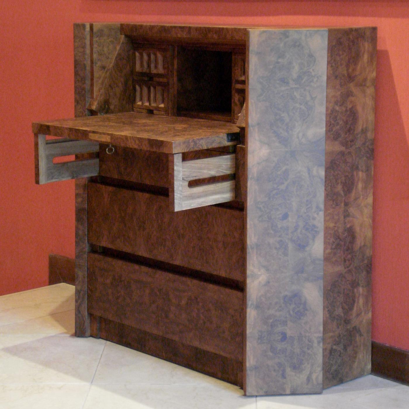 This imposing chest in walnut root features four small decorated top drawers and three large ones under the frontal flap door that can be used as a desk.