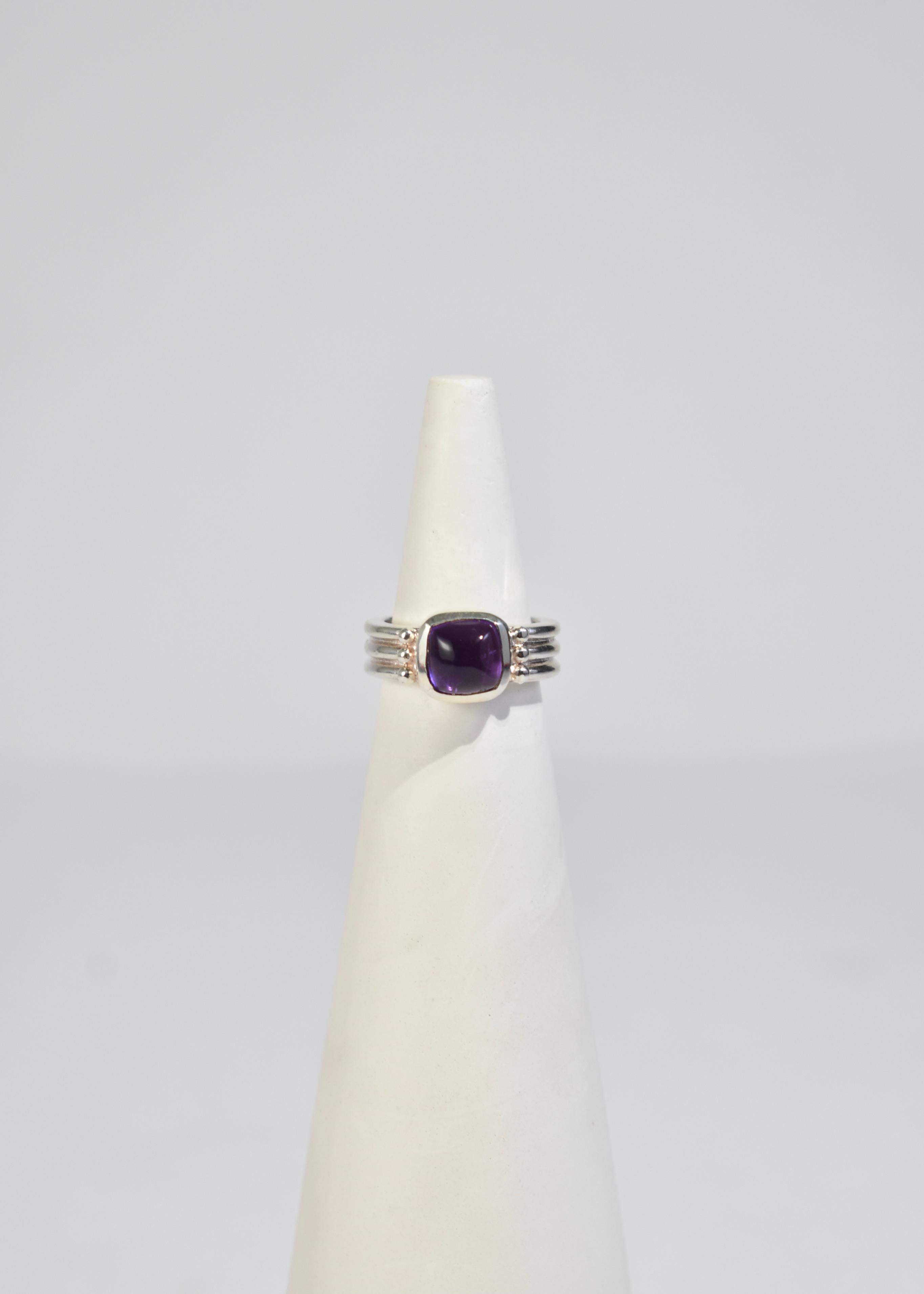 Vintage sterling ring with a polished amethyst cabochon and ribbed detail, stamped 925.

Material: Sterling silver, amethyst. 