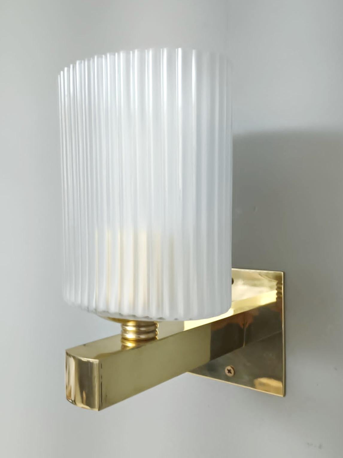 Italian wall lights with frosted white ribbed Murano glass shades mounted on brass frames / Made in Italy in the style of Barovier e Toso, circa 1950s.
Measures: height 9 inches, width 5 inches, depth 6 inches, backplate width 4 inches and height 4