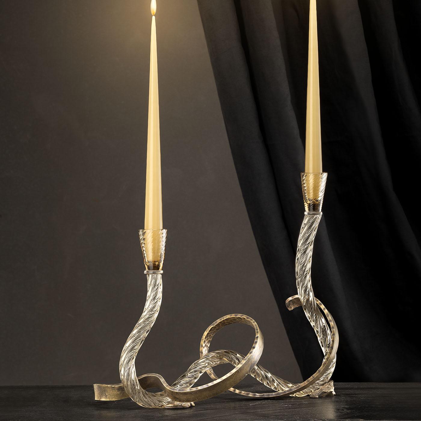 The Ribbon Murano Glass Candle Holder features a fluid, sinuous silhouette with hand-curved brass accents that create an artistic interplay of form and texture. This item offers two holders with a unique design that highlights the rich depth and