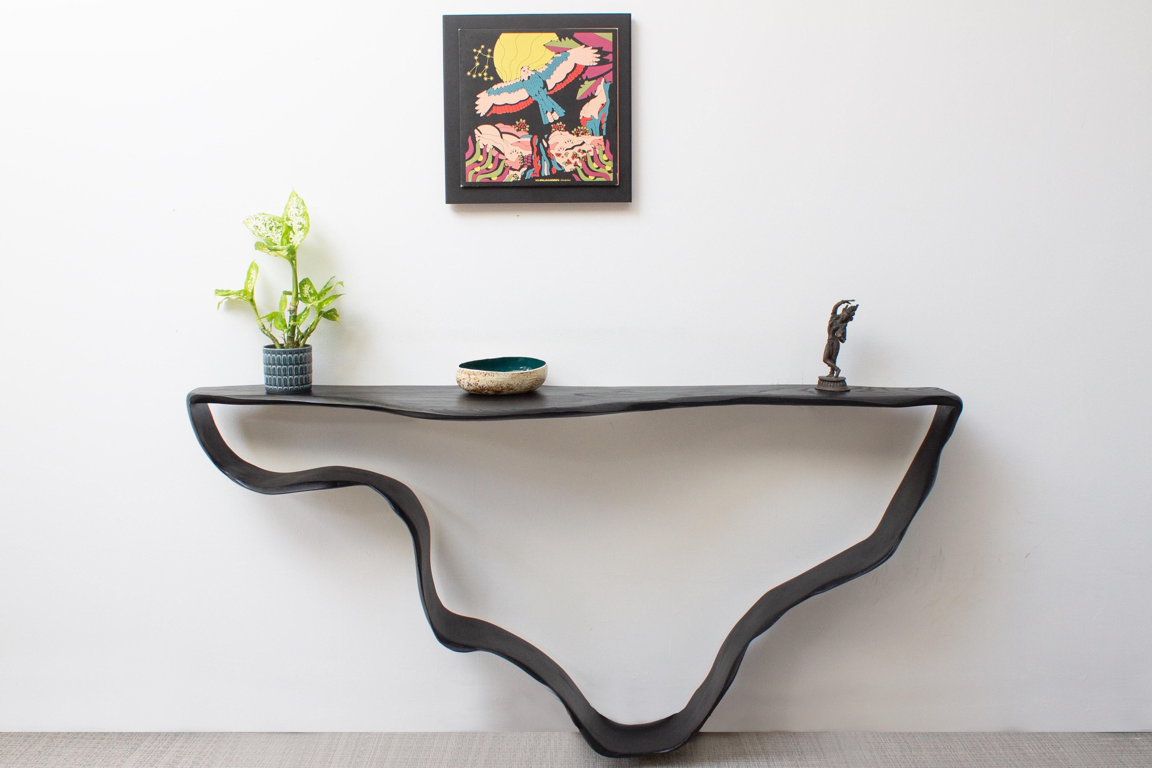 Cette table console sculpturale évoque un sentiment de mystère et de fluidité. Il y a divers éléments tirés du bois flotté érodé et des mouvements fluides et lisses d'un ruban.

Il a été conçu de telle sorte que nous pensons que la pièce entière est