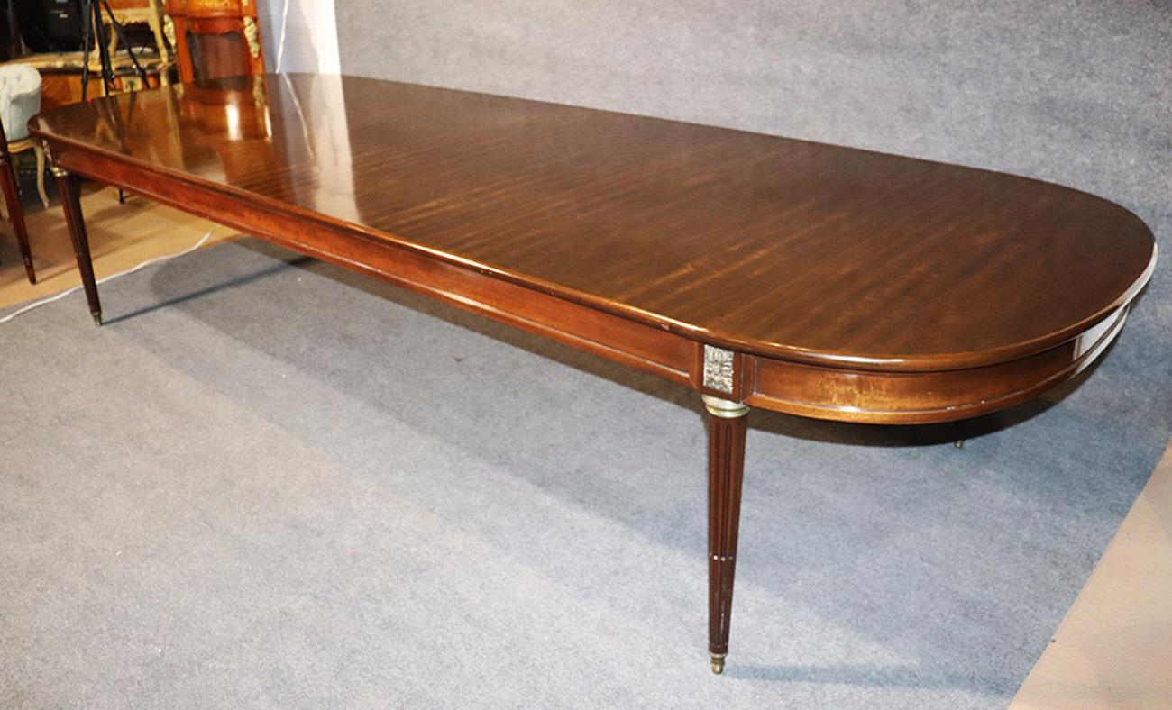 This is an enormous fixed top, one piece dining or perhaps conference table. The table features gorgeous ribbon mahogany and bronze Ormolu. The bronze is very beautifully cast and the wood quality is gorgeous with a wonderful walnut hue. The table