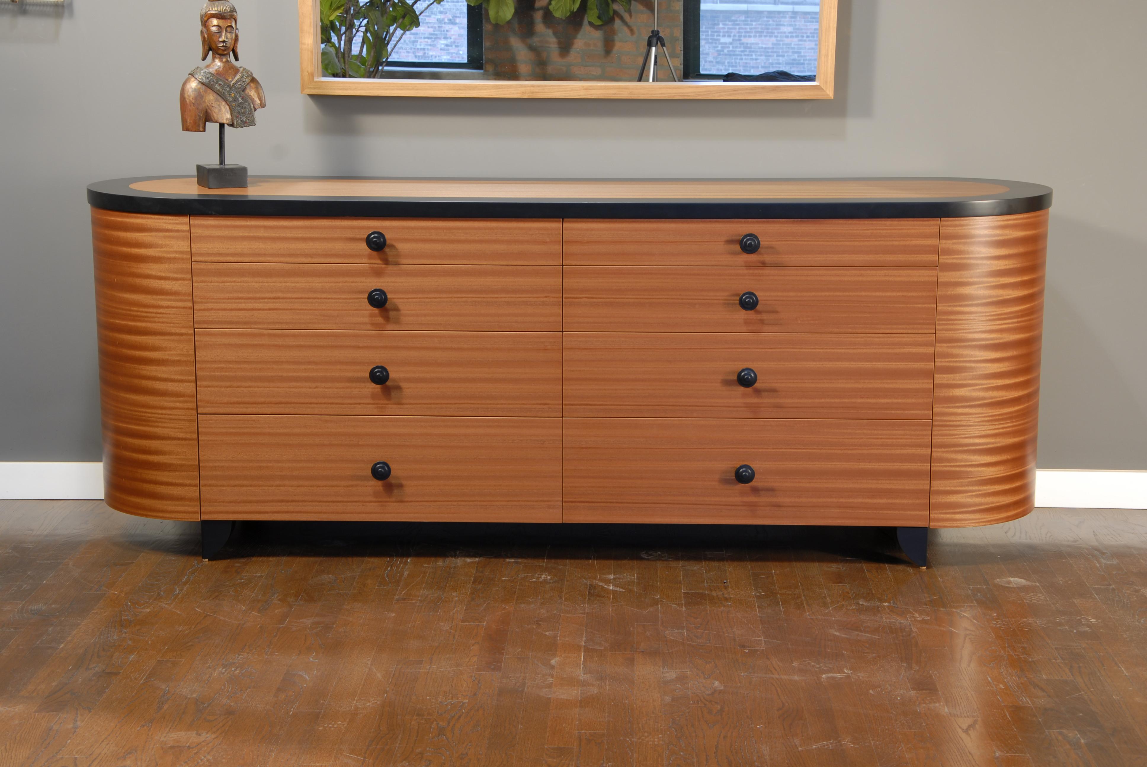 The eight drawer Elysia Dresser / Chest of drawers is shown in natural Ribbon Sapeli with black detailing. 34