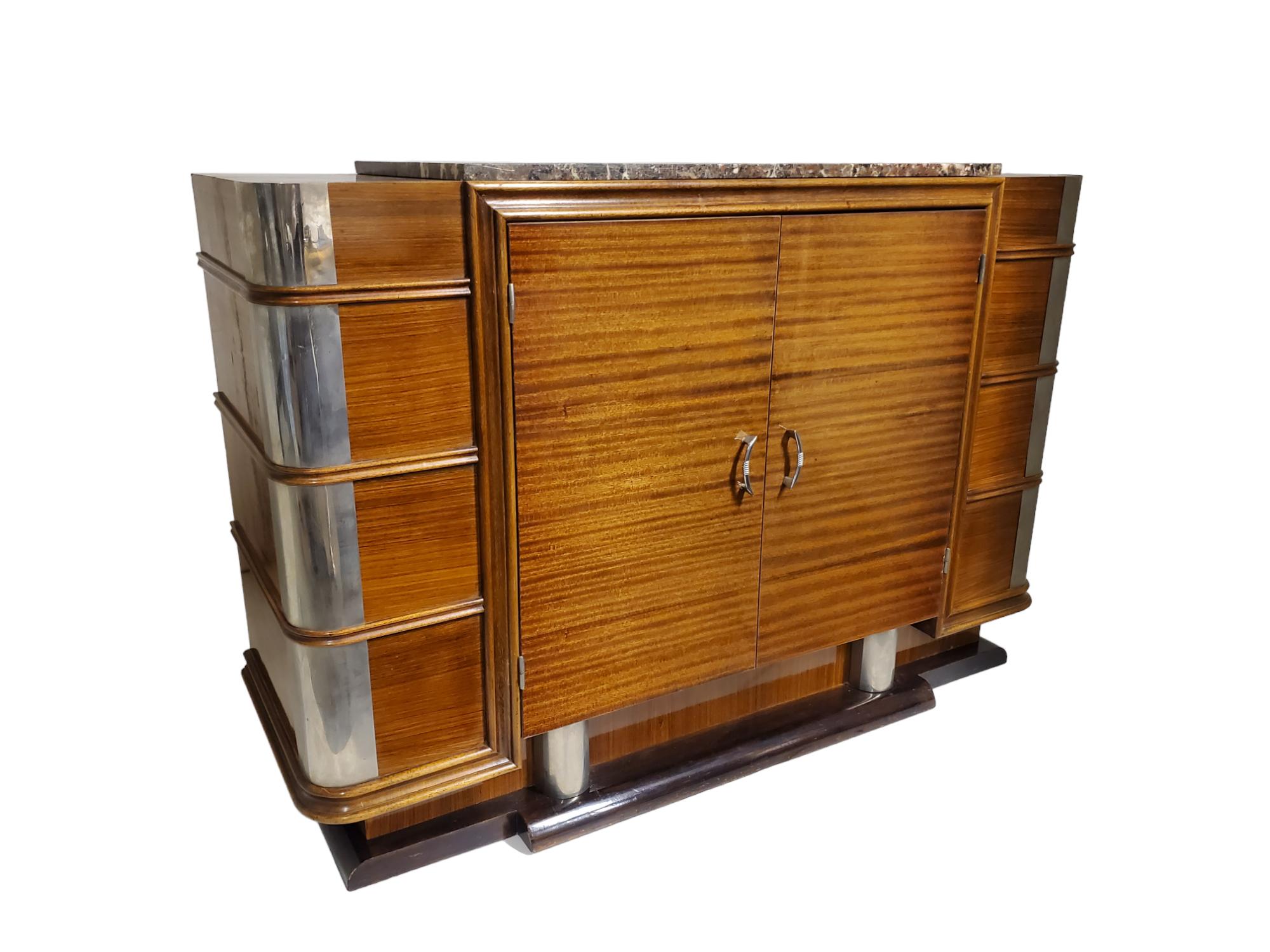 This French Modernist buffet features a captivating ribbon stripe mahogany design. Adding a touch of uniqueness, the polished nickeled bronze mounts highlight the rounded corners of the cabinet, resembling a protective armor. 
The horizontal grain
