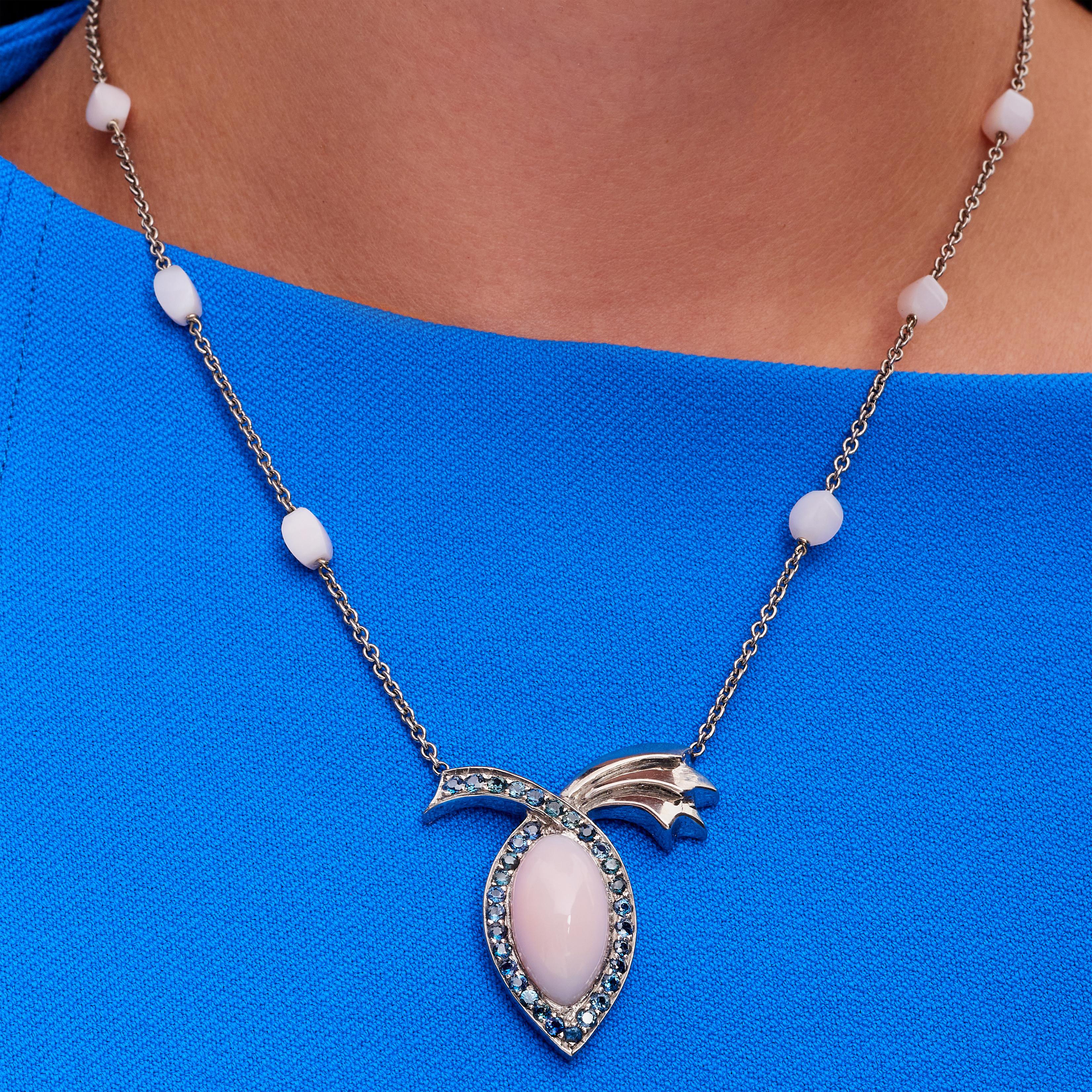 11.89 Carat Peruvian Pink Opal Blue Sapphire Pendant Necklace, In Stock.

This pendant necklace features a high dome marquise cut pink opal that is 11.898 carats. It is surrounded by round brilliant-cut blue sapphires that have a 2.53-carat total