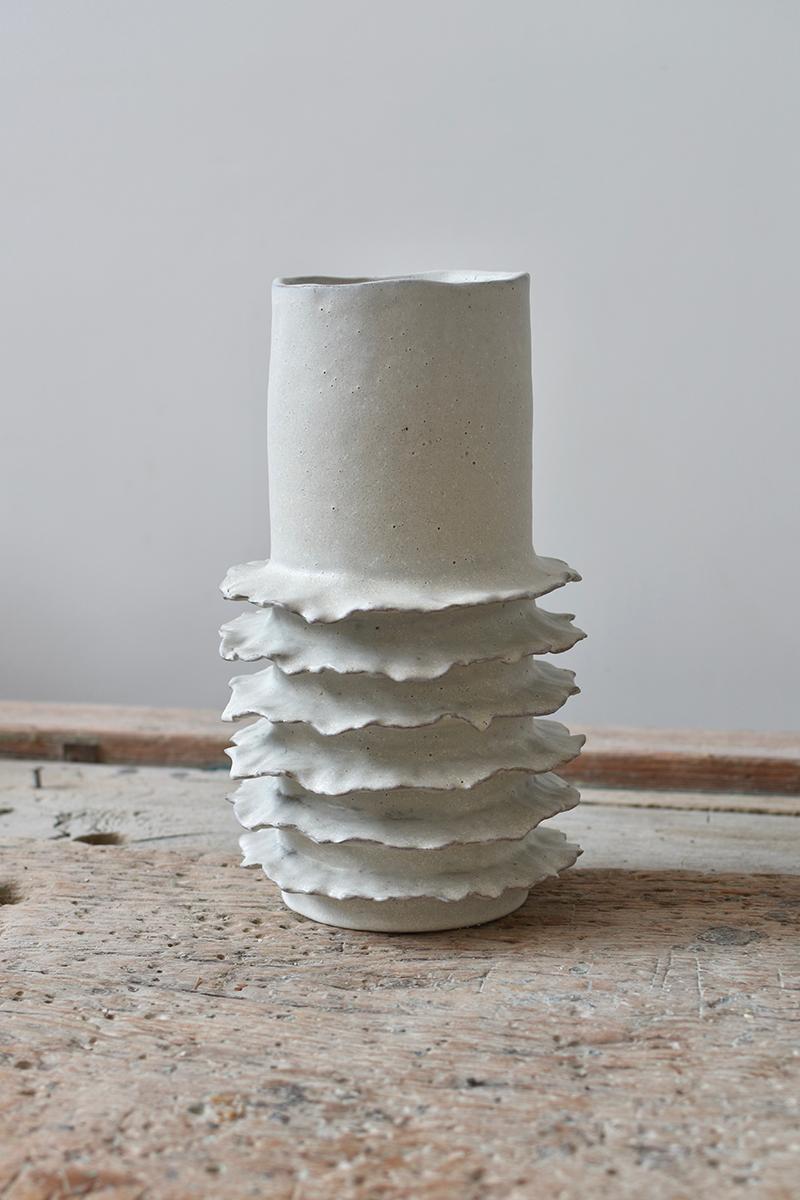 Bellissimo vaso costiero realizzato in gres. Ispirato alla vibrante vita marina della barriera corallina e al morbido movimento delle onde dell'oceano, questo vaso bianco opaco mostra una miscela distintiva di arte e natura, catturando la tranquilla