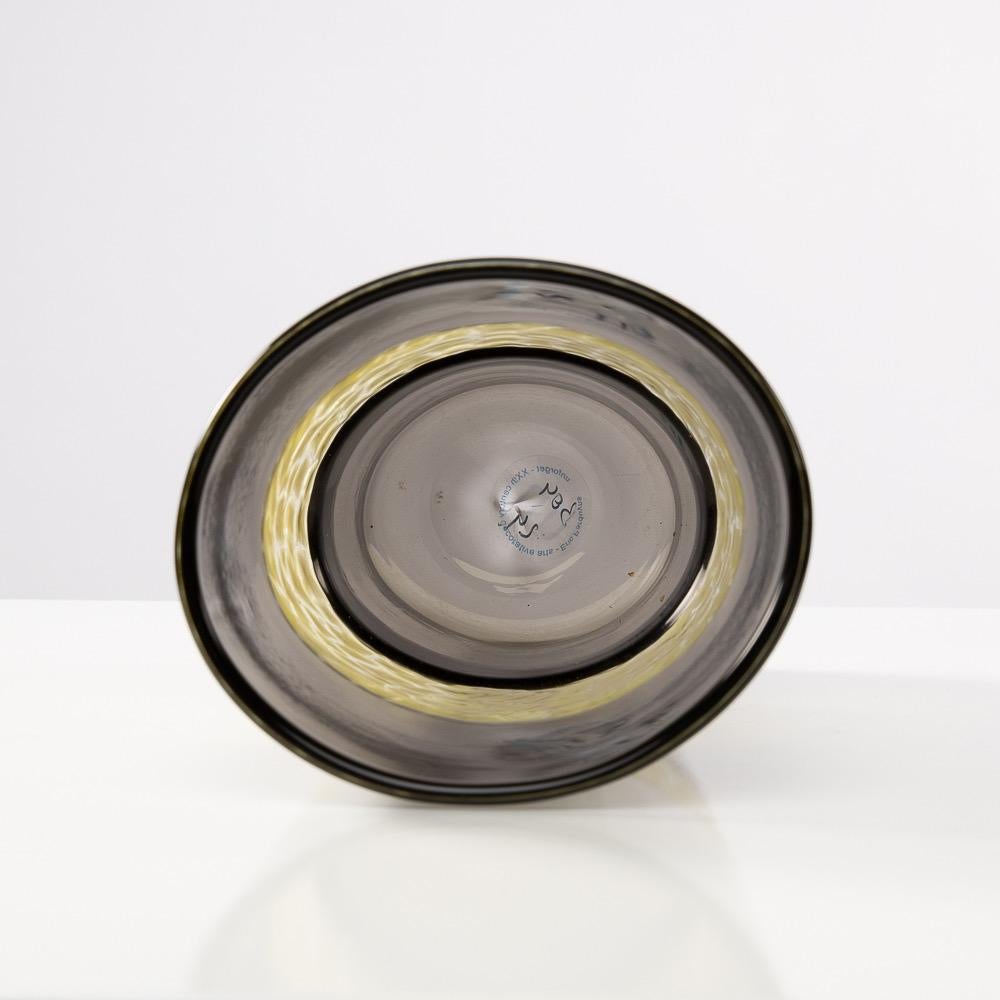 Raro vaso a doppio incalmo con murina centrale.
Il corpo del vaso è in vetro soffiato di Murano color grigio talpa.
Una murina centrale bianca e gialla è fissata tra le due bande di vetro. Il murino ha un motivo 