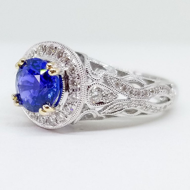 A Contemporary Crafted Engagement or Cocktail Ring is set with a Very Fine, AAA 1.70 Carat Round Brilliant Cut Blue Sapphire of Medium Burma Blue Hue and Fine Gem Quality. This Expertly cut stone is set in four pair of double prongs and is