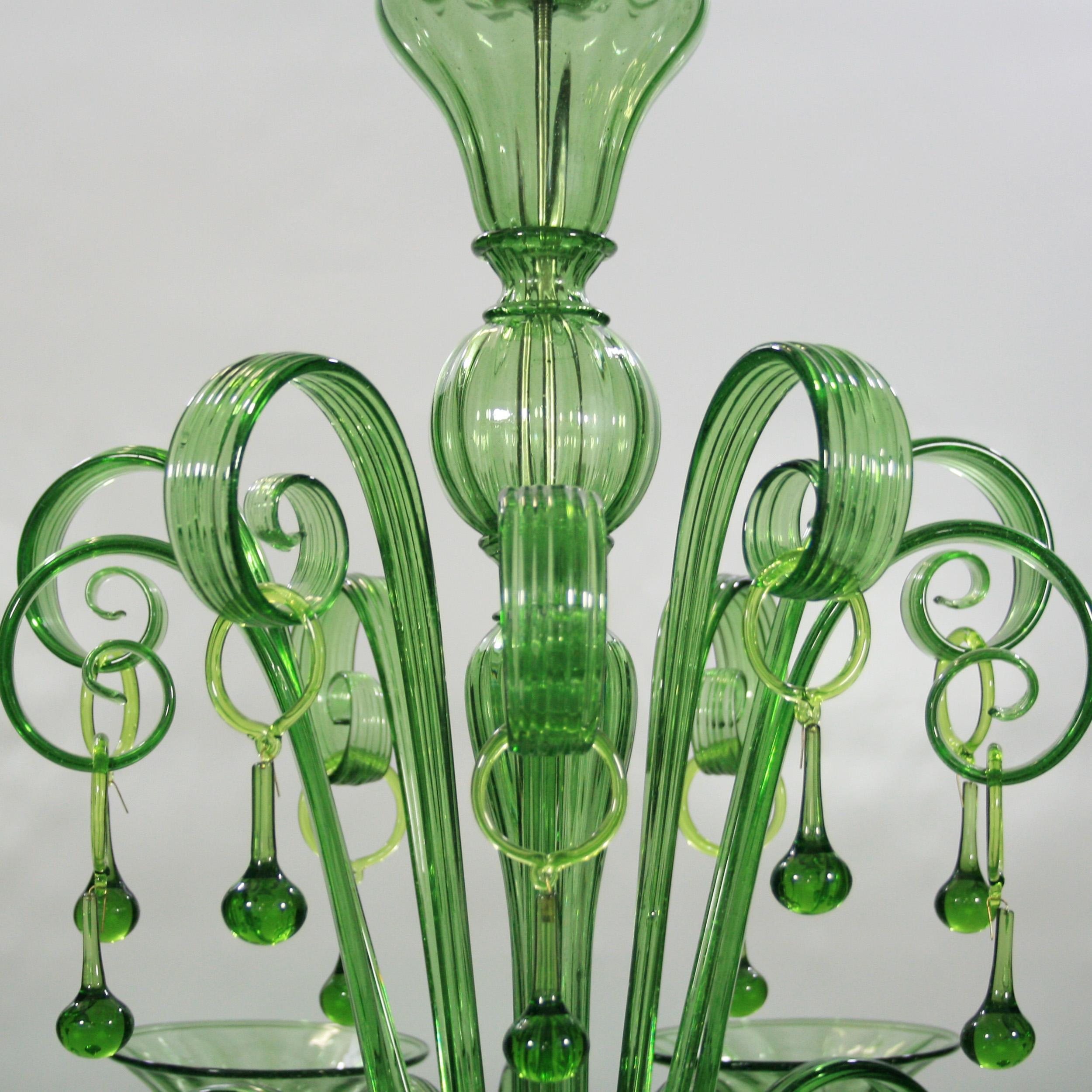 Rich chandelier by Multiforme with 6 lights, in green artistic glass, with curly ornamental elements. The lights are upwards.
Inspired by the Classic Venetian tradition it is characterized by a central column where many blown glass “pastoral”