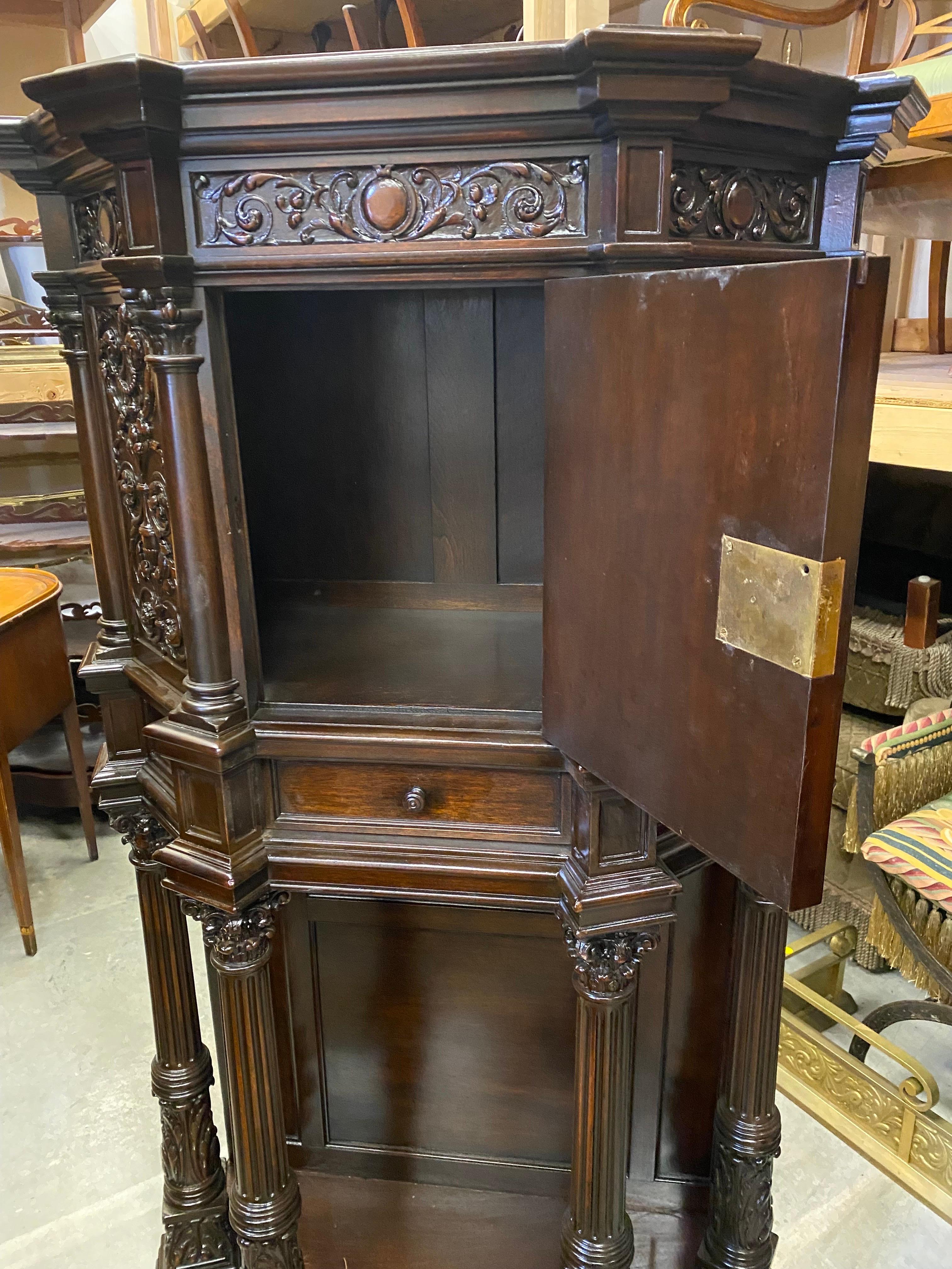 Handsome and stately hand carved English Tudor court cupboard. The top section with door with elaborately hand carved panels above a single drawer. the open storage base with carved columns with acanthus leaf at the bottom. This piece has been fully