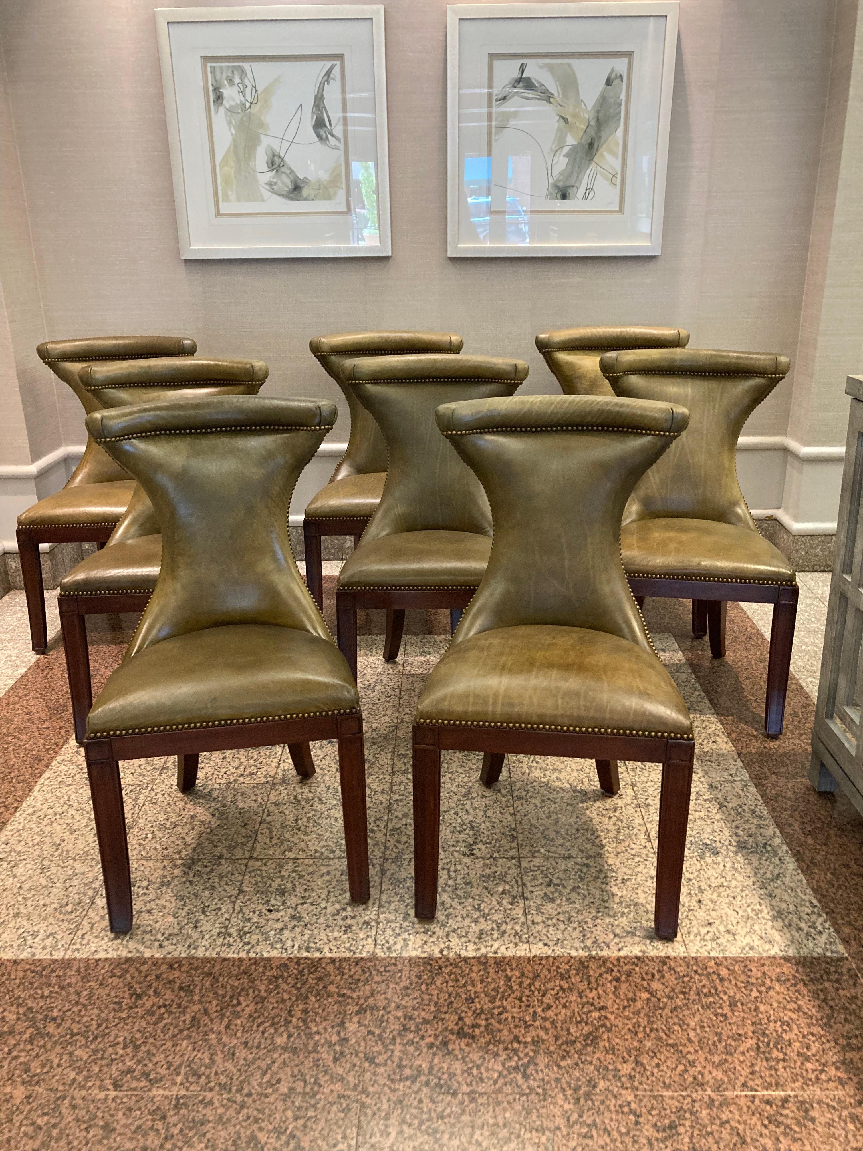 Striking moss green leather dining chairs with rich patinated appearance having various shades of green which give the chairs depth and character.   Wooden legs and nailhead trim.  


