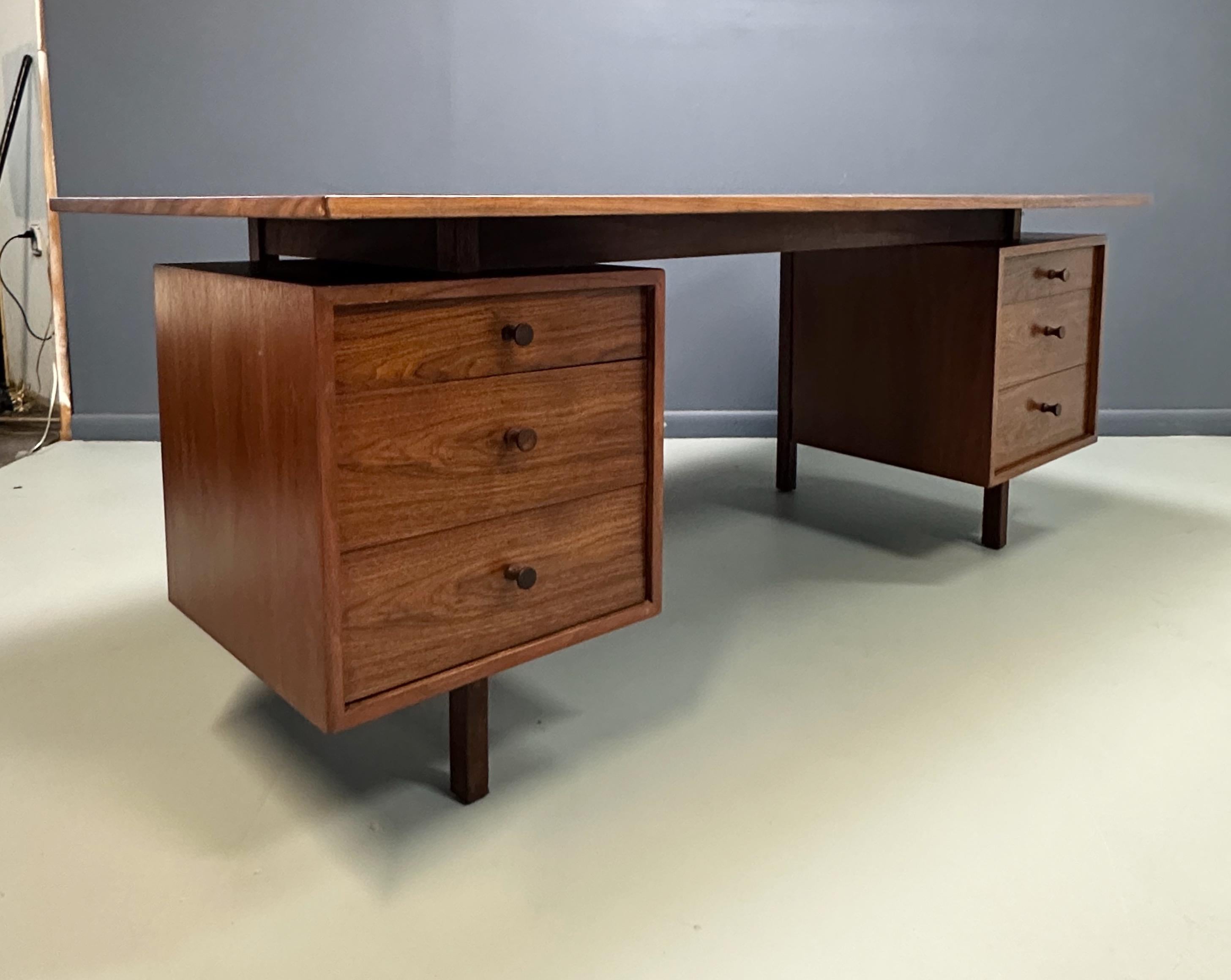 Un'imponente e raffinata scrivania direzionale dell'artista e designer americano Richard Artschwager, realizzata in noce riccamente scolpito. Il design è caratterizzato da un piano rettangolare fluttuante sostenuto da due basi a piedistallo,