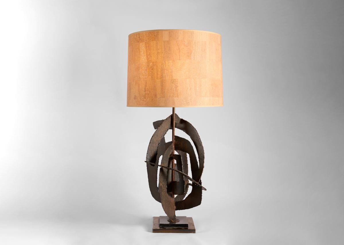 Ribbons of torched steel loop round a central rod to form multiple planes on each of these remarkable Brutalist table lamps.