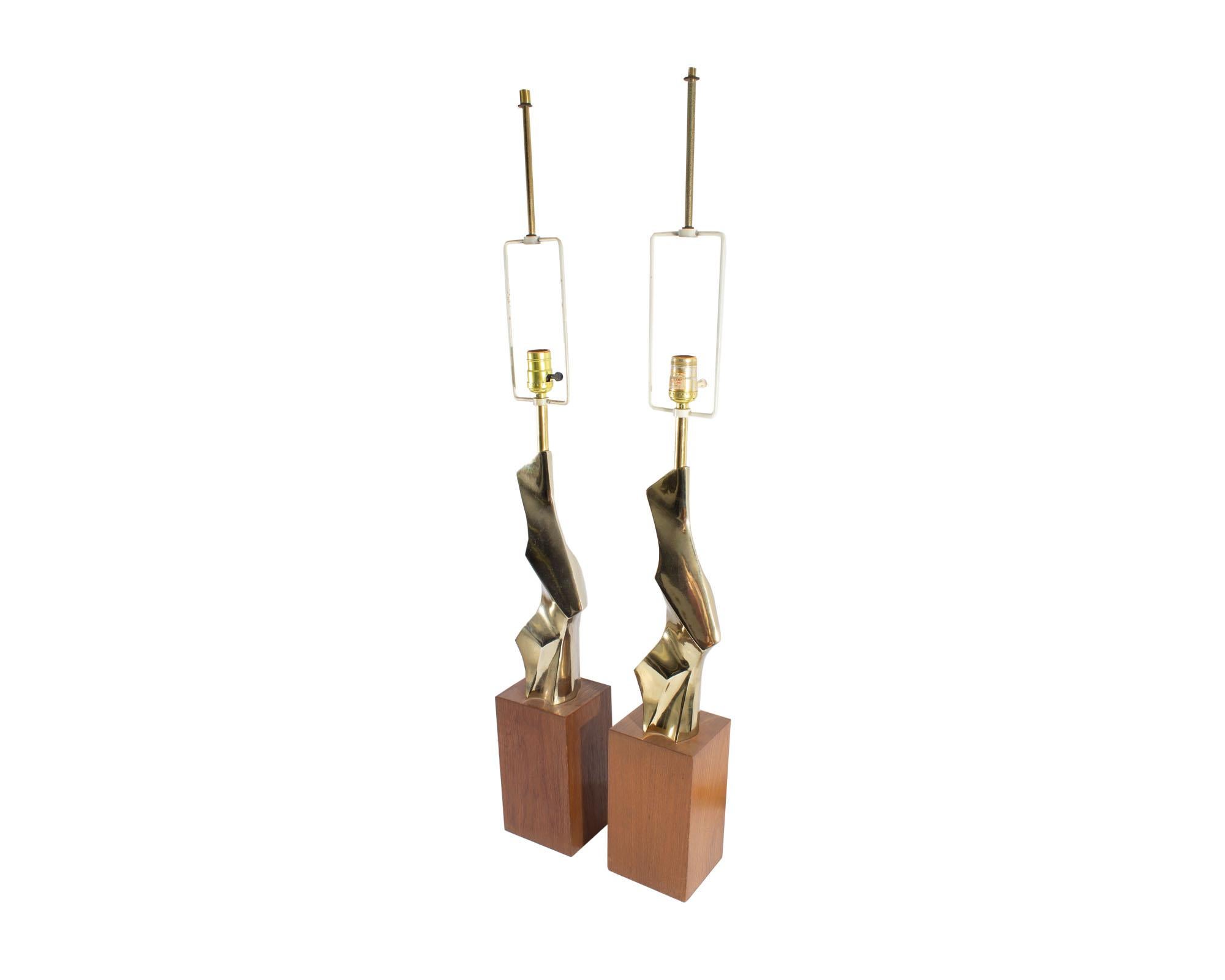 A pair of Mid Century Modern table lamps designed by Richard Barr for the Laurel Lamp Company. These Brutalist table lamps feature a brass abstract form that stands on a wooden base. One of the lamps is marked with a Laurel sticker to its