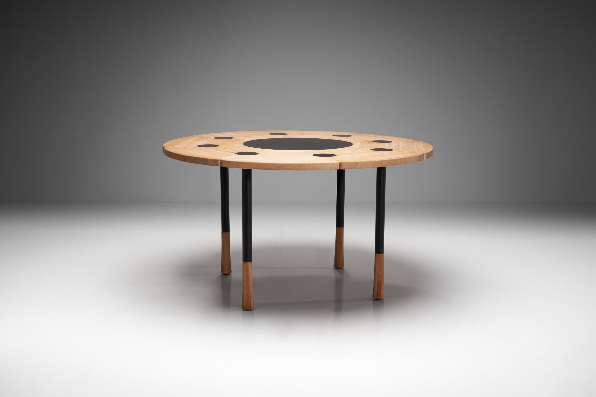 This extraordinary sculptural round dining table has strong lines and proportions and was made in very small numbers.

The table consists of eight beech elements that have a petal like shape. The elements are connected with eight black metal round