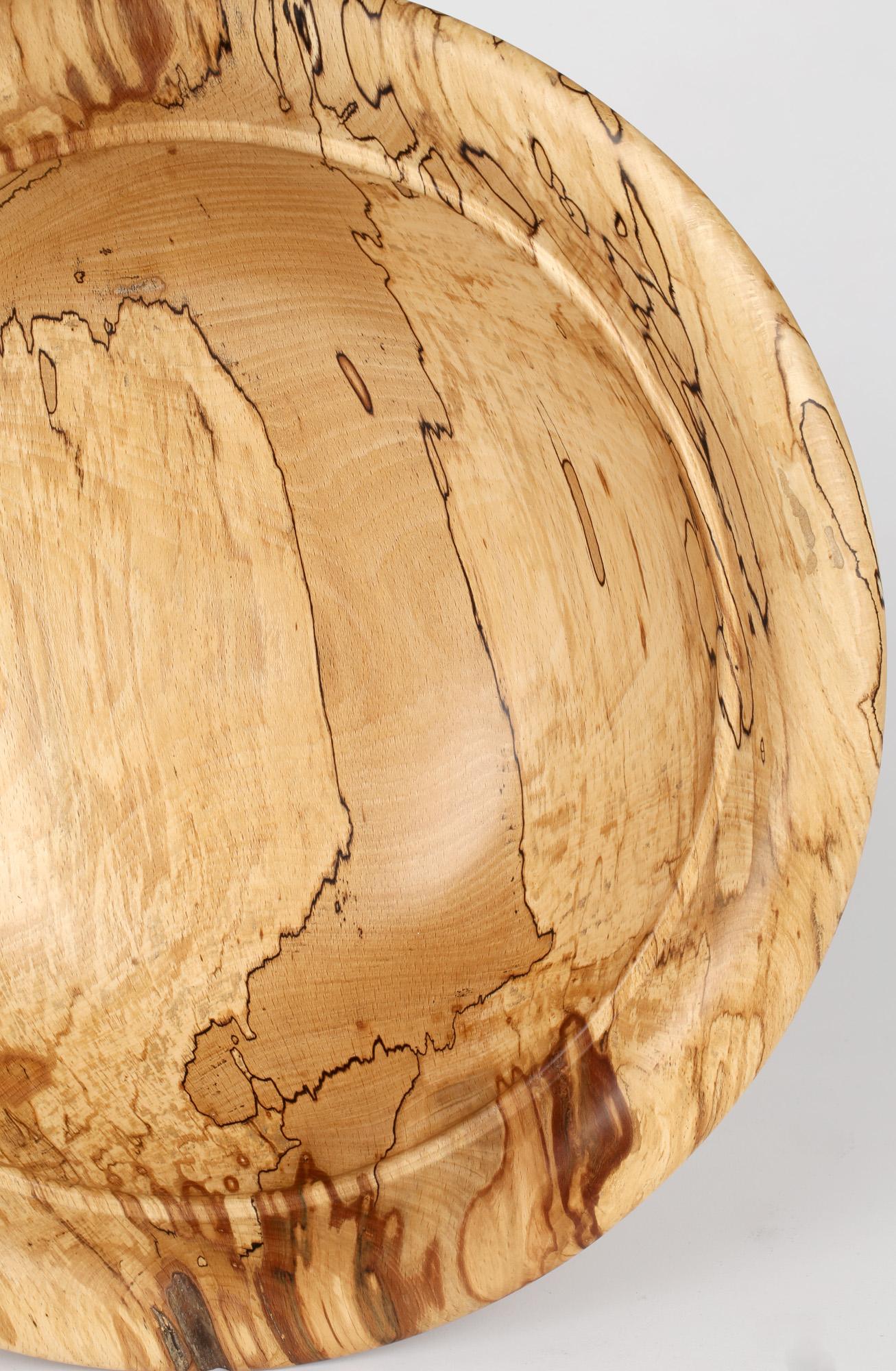 A fine English hand crafted large turned spalted beech wood bowl by Richard Chapman (b.1951) and dating from the 20th century. The large rounded bowl stands on a narrow rounded foot with slightly recess carved base. The bowl has a rounded body with