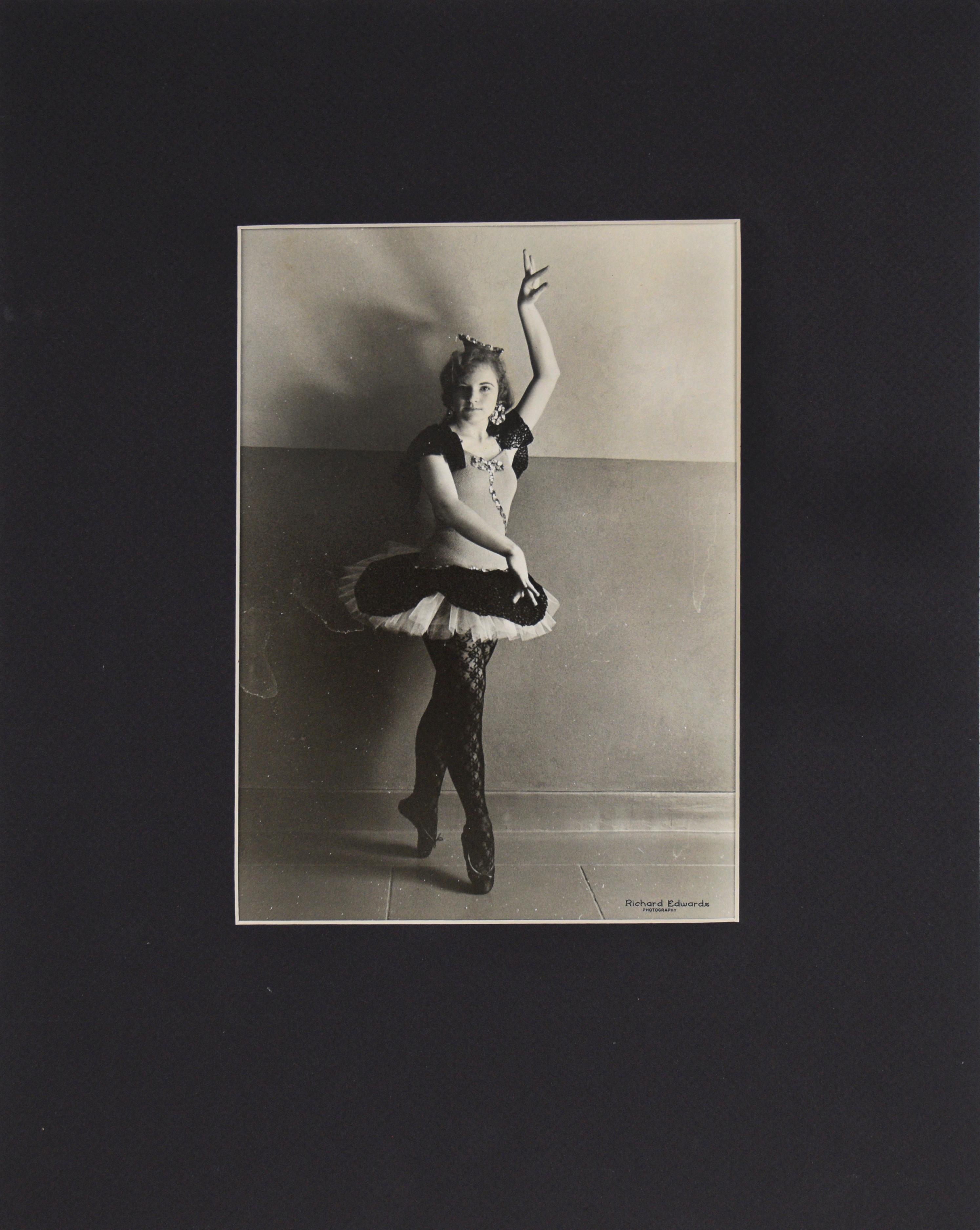 Young Ballerina In Pose San Francisco Richard Edwards

Photo of a young ballerina posing. She is holding her right hand above her head, while her left hand is posed in front of her. The young girl is wearing a black and white tutu, a black lace