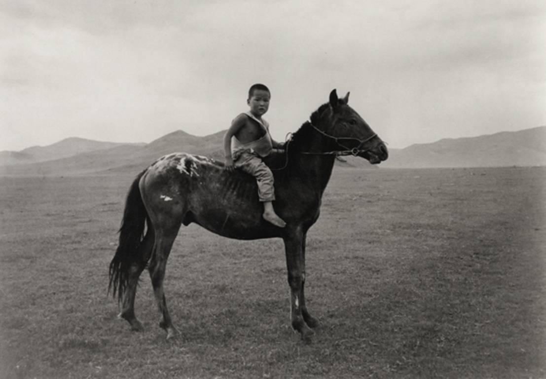 A beautifully composed, ethereal, silver gelatin print of a young Mongolian boy on horseback in the morning mist by actor/ activist/ photographer Richard Gere. This limited edition print is featured in Gere's book 