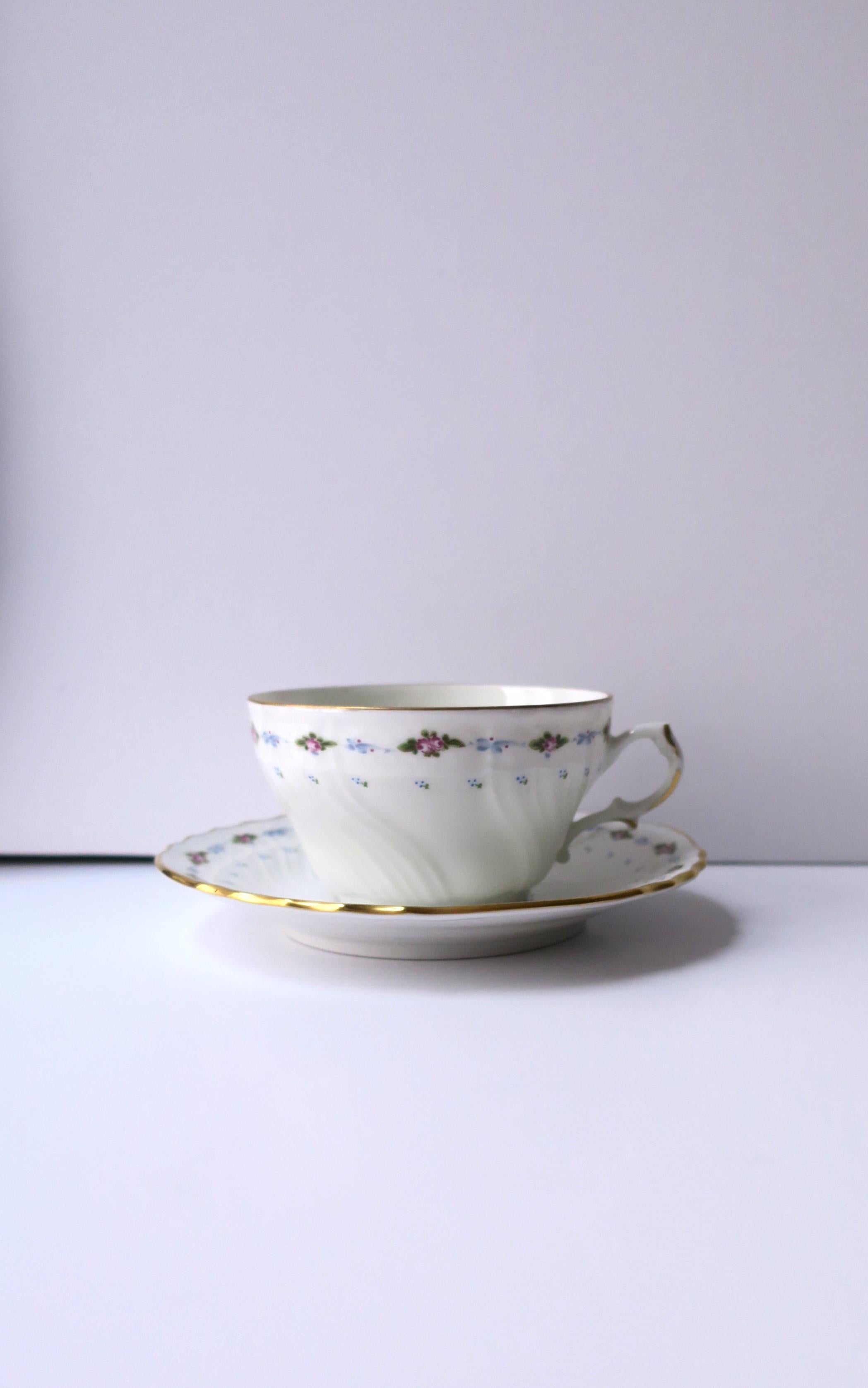 An Italian white porcelain coffee or tea cup and saucer, with floral design, by designer Richard Ginori, 1991, Italy. Both cup and saucer have a blue, green, and purple design of flowers and leaves around, finished with gold detail. A beautiful way