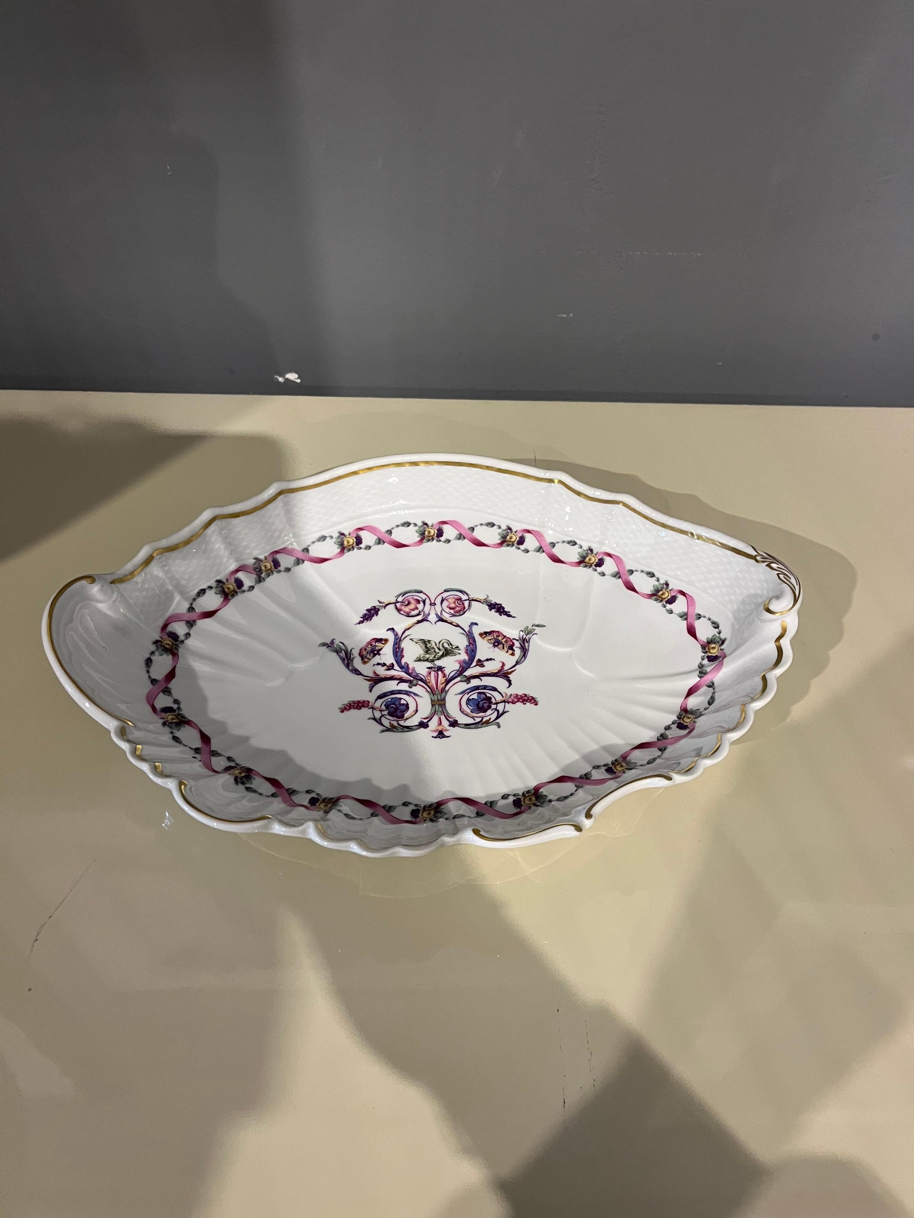 Un’eleganza sottile e senza tempo prende forma in questo raffinato piatto in porcellana Richard Ginori, dove la delicatezza dei decori floreali si intreccia con la perfezione delle linee classiche. La sua forma leggermente mossa, i profili finemente
