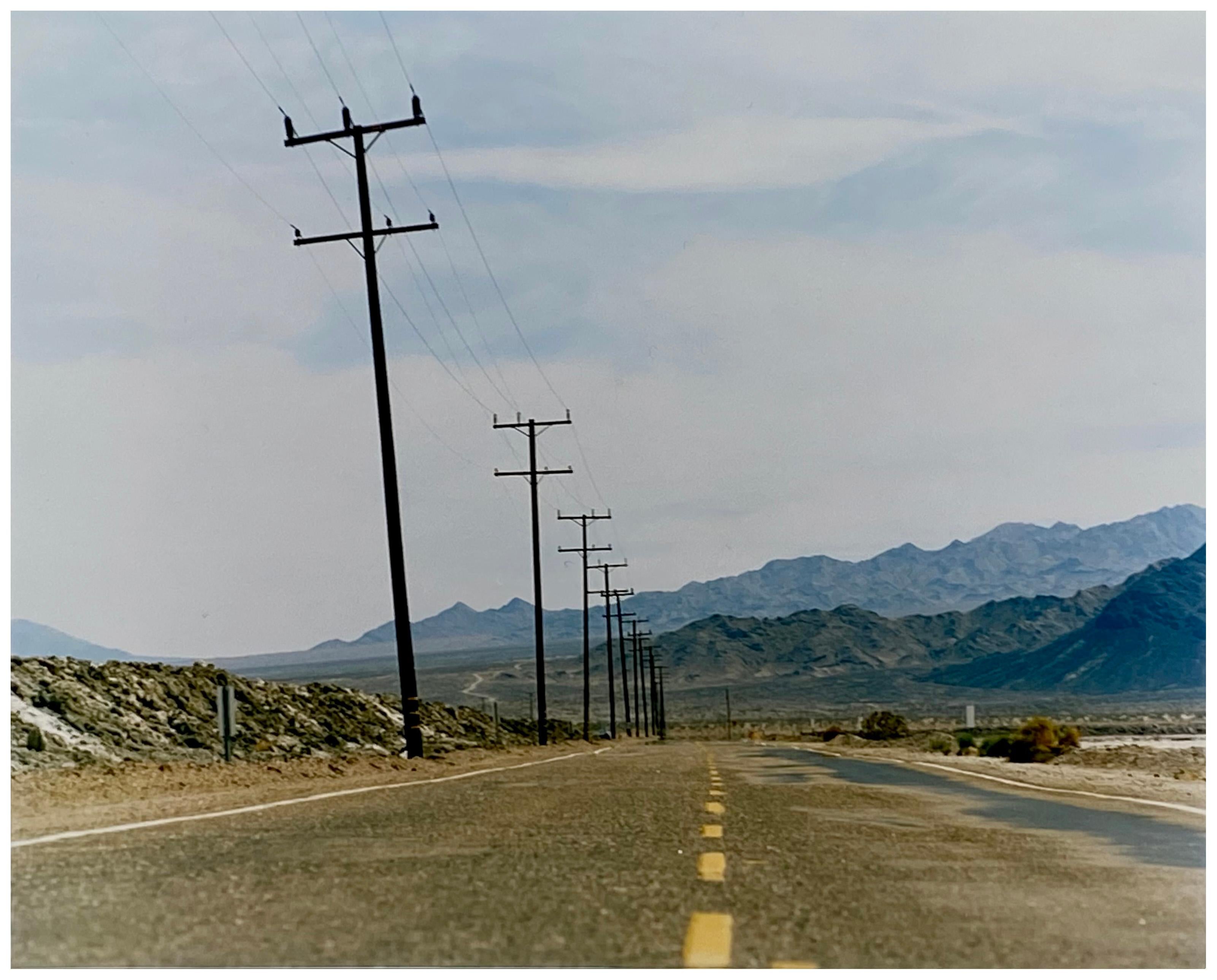 An open road in Amboy, California, featuring telephone poles disappearing into the mountainous distance. This classic and timeless landscape photograph is part of Richard Heeps' 'Dream in Colour' series. 

This artwork is a limited edition of 25,
