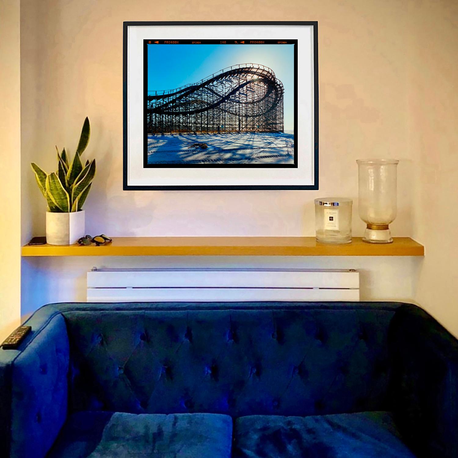 Gestrandete Achterbahn, Foto aus der Serie Jersey Shore von Richard Heeps. Die Schlafstruktur am Strand hat etwas Friedliches an sich und steht im Gegensatz zum Echo der Schreie in der Hochsaison, die man im Kopf hat.

Dieses Kunstwerk ist ein auf
