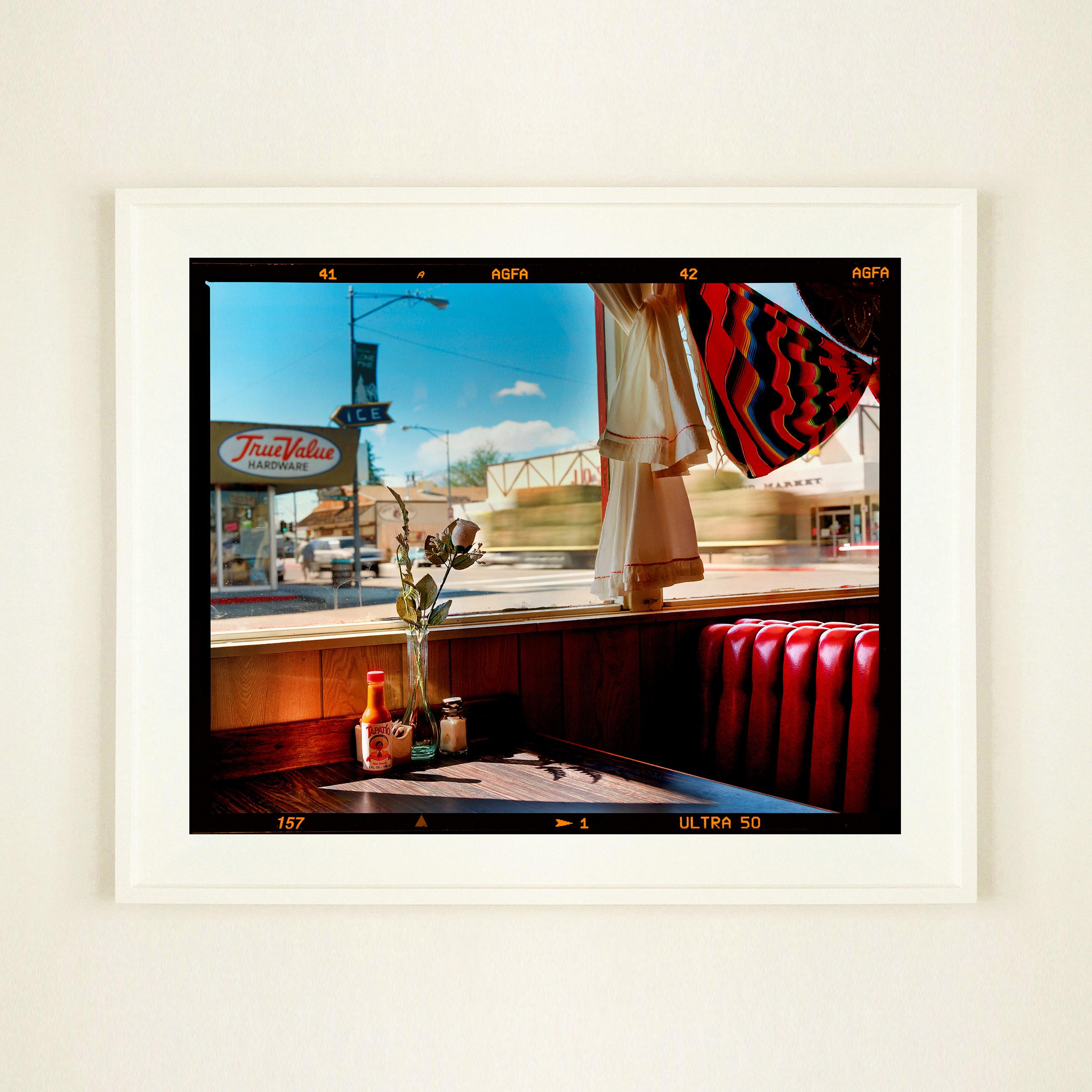Bonanza Café, photographie emblématique de la série Dream in Colour de Richard Heeps, qui a servi de couverture à son livre Man's Ruin. La photo vous ramène dans une petite ville américaine, avec le soleil qui pénètre par les fenêtres sur les sièges