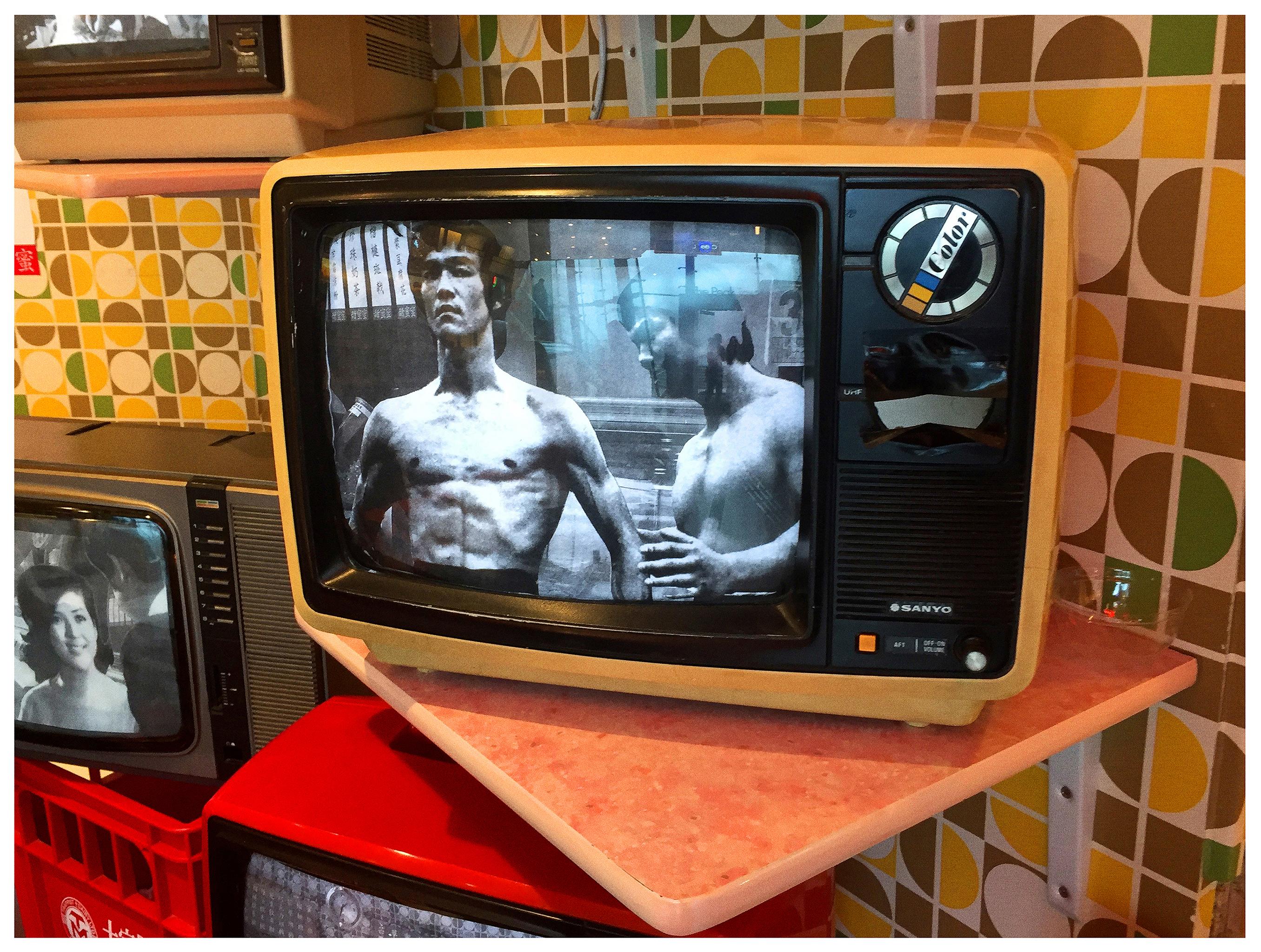 Bruce Lee TV, photograph by Richard Heeps captured at the top of Victoria Peak in Hong Kong. Seventies inspired mustard wallpaper is the backdrop for a black and white vintage Sanyo TV featuring Martial Arts icon Bruce Lee.  

This artwork is a
