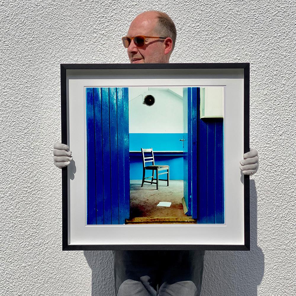 Ein Stuhl steht in einer verfallenen Fabrik in einem blau gestrichenen Raum, die Tiefenperspektive erzeugt einen Farbblockierungseffekt. 
aus Richard Heeps 