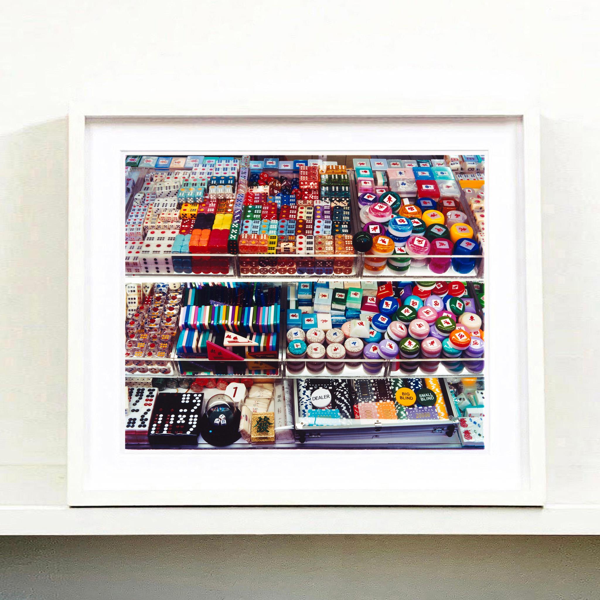 Marchand, photographie de rue de la série de Richard Heeps, The Streets of Hong Kong. L'objectif de Richard pour sa série City est de représenter l'empreinte digitale d'un lieu. Ici, le magasin de rue vendant des accessoires de jeu est une métaphore