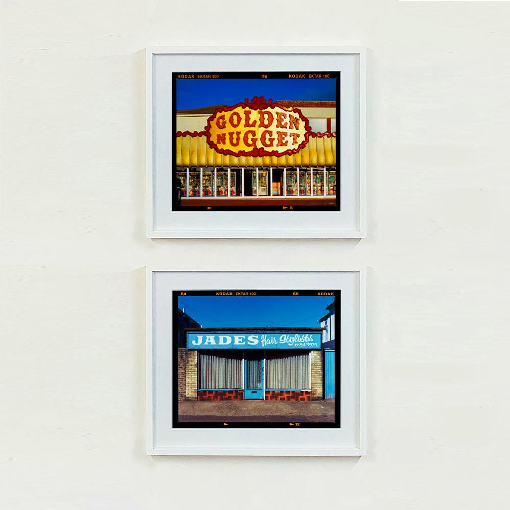 Golden Golden Nugget, Arkadenfassade am Meer in der Dämmerung, Typografie-Fotografie aus der Serie On-Sea von Richard Heeps.

Dieses Kunstwerk ist ein auf 25 Exemplare limitierter fotografischer Glanzabzug vom Negativ, trocken auf Aluminium