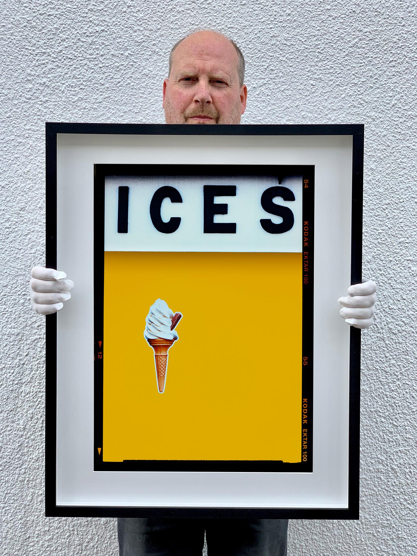 ICES, by Richard Heeps, photographed at the British Seaside at the end of summer 2020. This artwork is about evoking memories of the simple joy of days by the beach. The mustard yellow color blocking, typography and the surreal twist of the