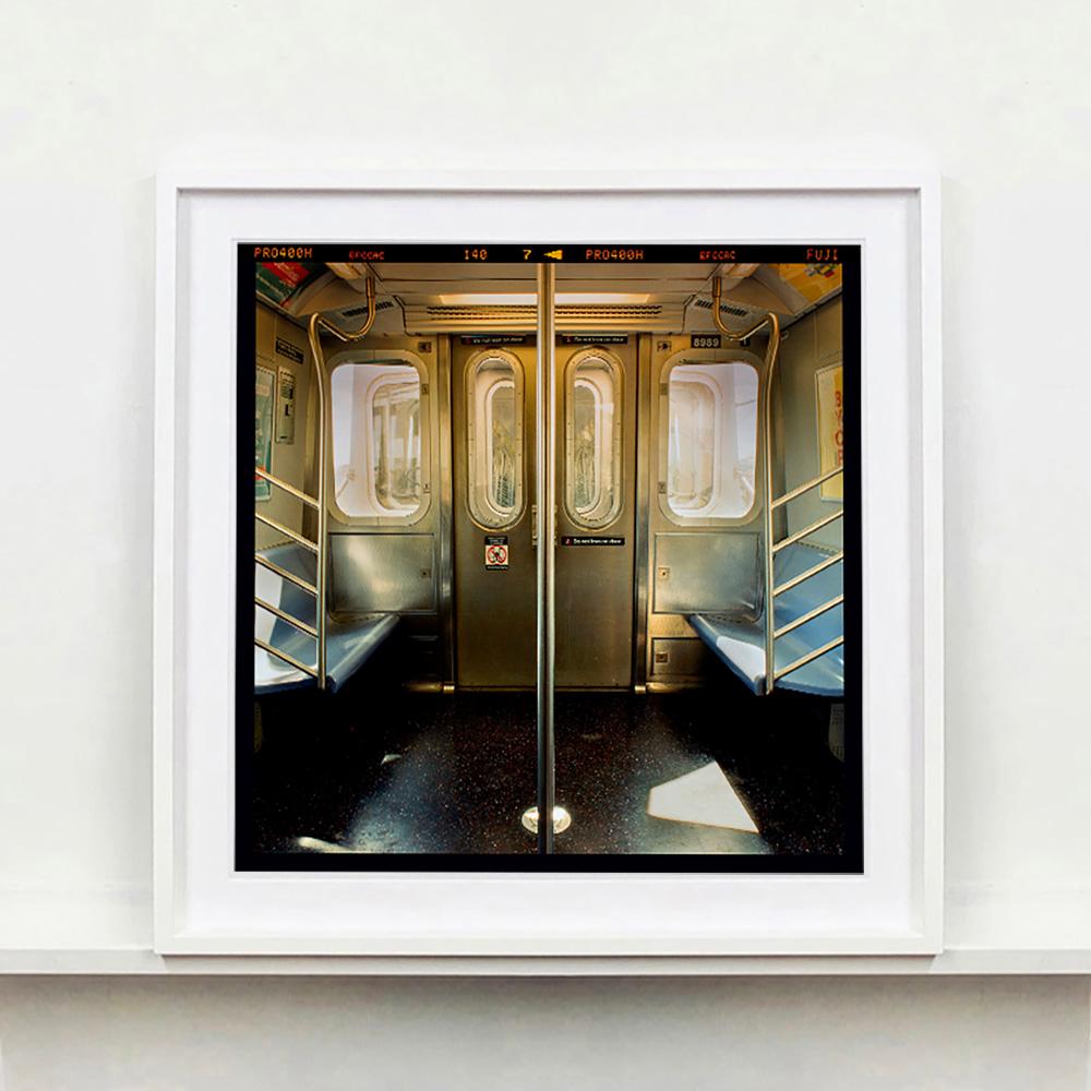 New York City Subway Car Innenaufnahme von Richard Heeps. Dieses stimmungsvolle Foto eines New Yorker U-Bahnwagens fängt die filmische Essenz des U-Bahnfahrens ein. Die Perspektive der Stange in der Mitte vermittelt dem Betrachter das Gefühl, sich