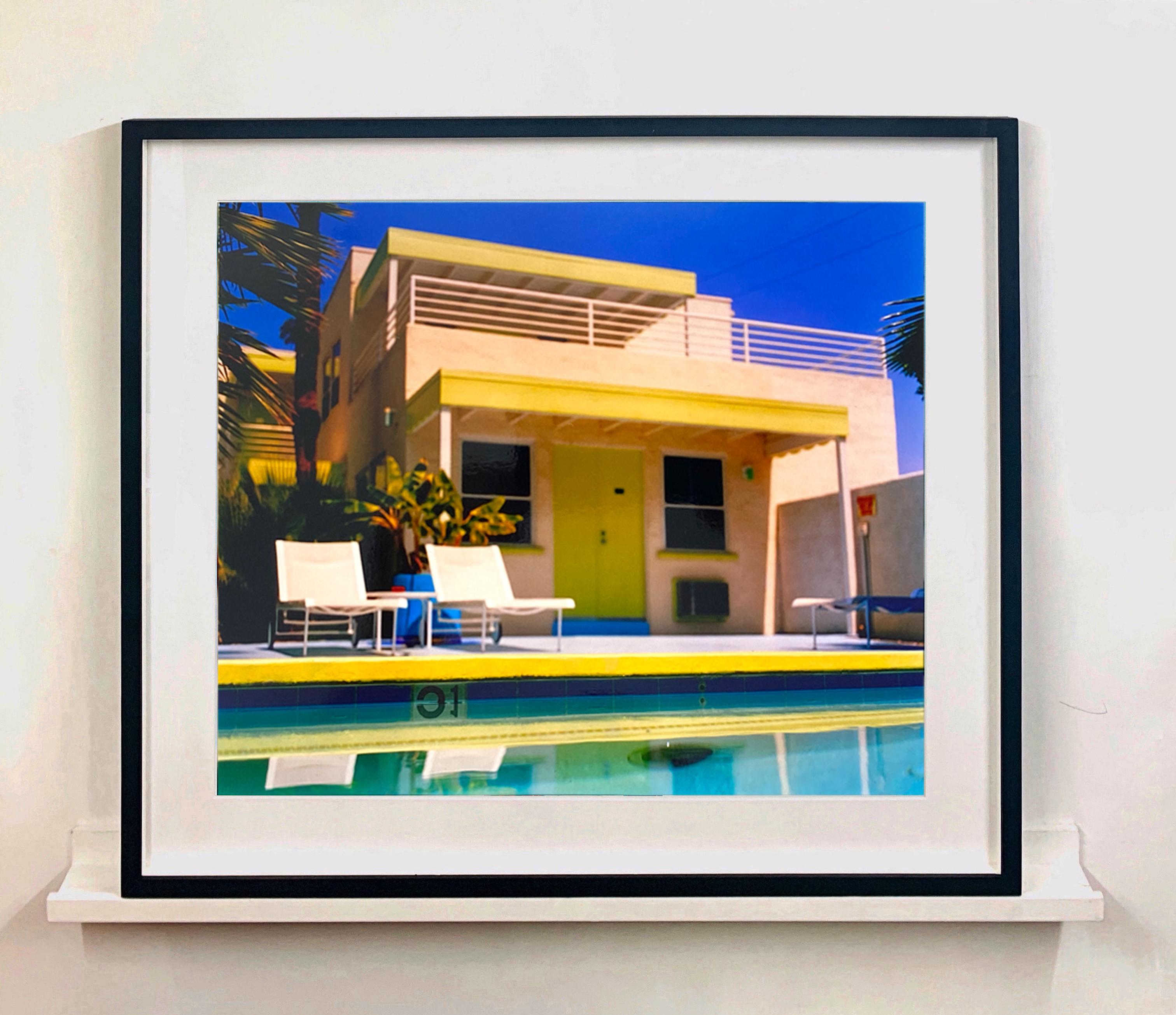 Palm Springs Pool Side, photograph by Richard Heeps taken at Ballantines Movie Colony. This artwork captures the classic mid-century Palm Springs architecture set against saturated blue skies and the cool pool with accents of pink and almost neon
