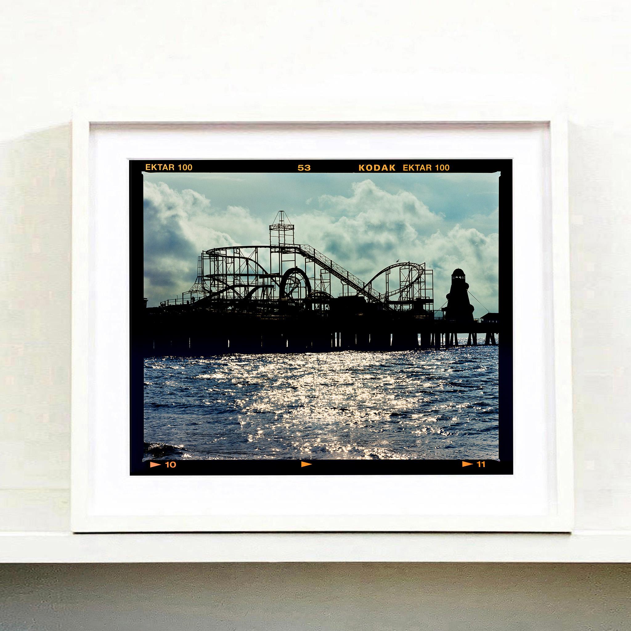 Pleasure Pier, photographie de paysage aquatique de la série On-Sea de Richard Heeps. Capturant la silhouette de la fête foraine à l'aube, cette jetée vers la mer pourrait presque être n'importe où.

Cette œuvre est une édition limitée de 25 tirages