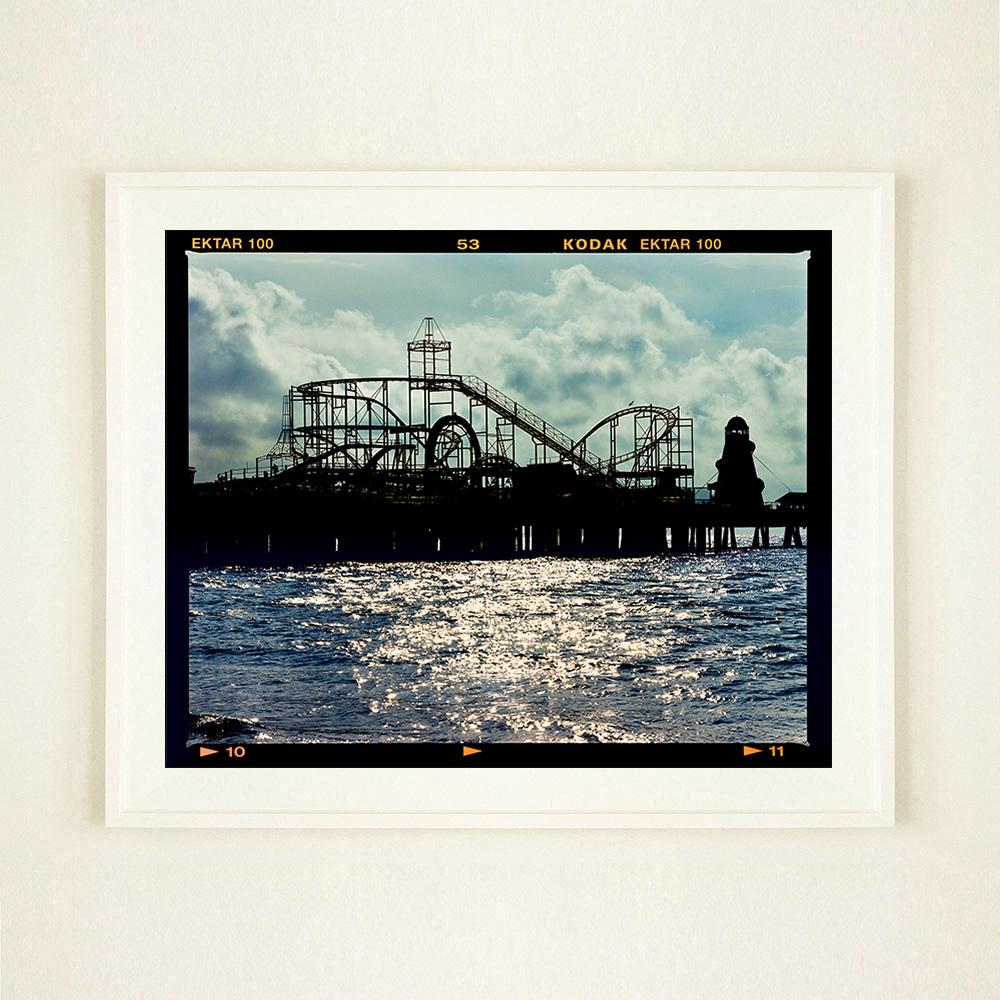 Pleasure Pier, Wasserlandschaftsfotografie aus der Serie On-Sea von Richard Heeps. Die Silhouette des Jahrmarkts in der Morgendämmerung könnte überall sein, wenn man den Pier im Meer sieht.

Dieses Kunstwerk ist ein auf 25 Exemplare limitierter