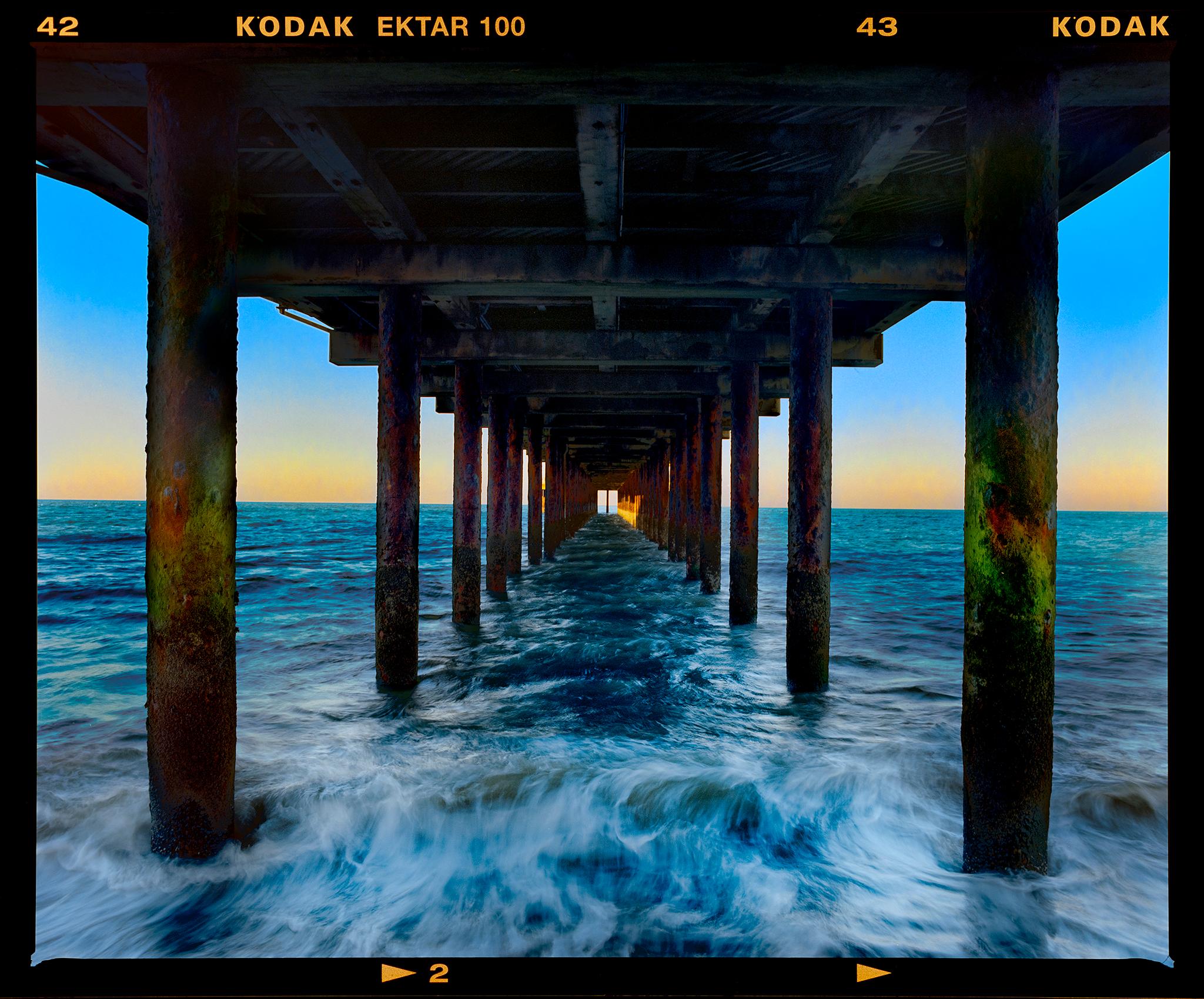 Southwold Pier, waterscape photograph from Richard Heeps' series, On-Sea. Symmetry of the architectural structure draws your eyes hypnotically to the horizon as the sun is setting on the sea.

This artwork is a limited edition of 25 gloss