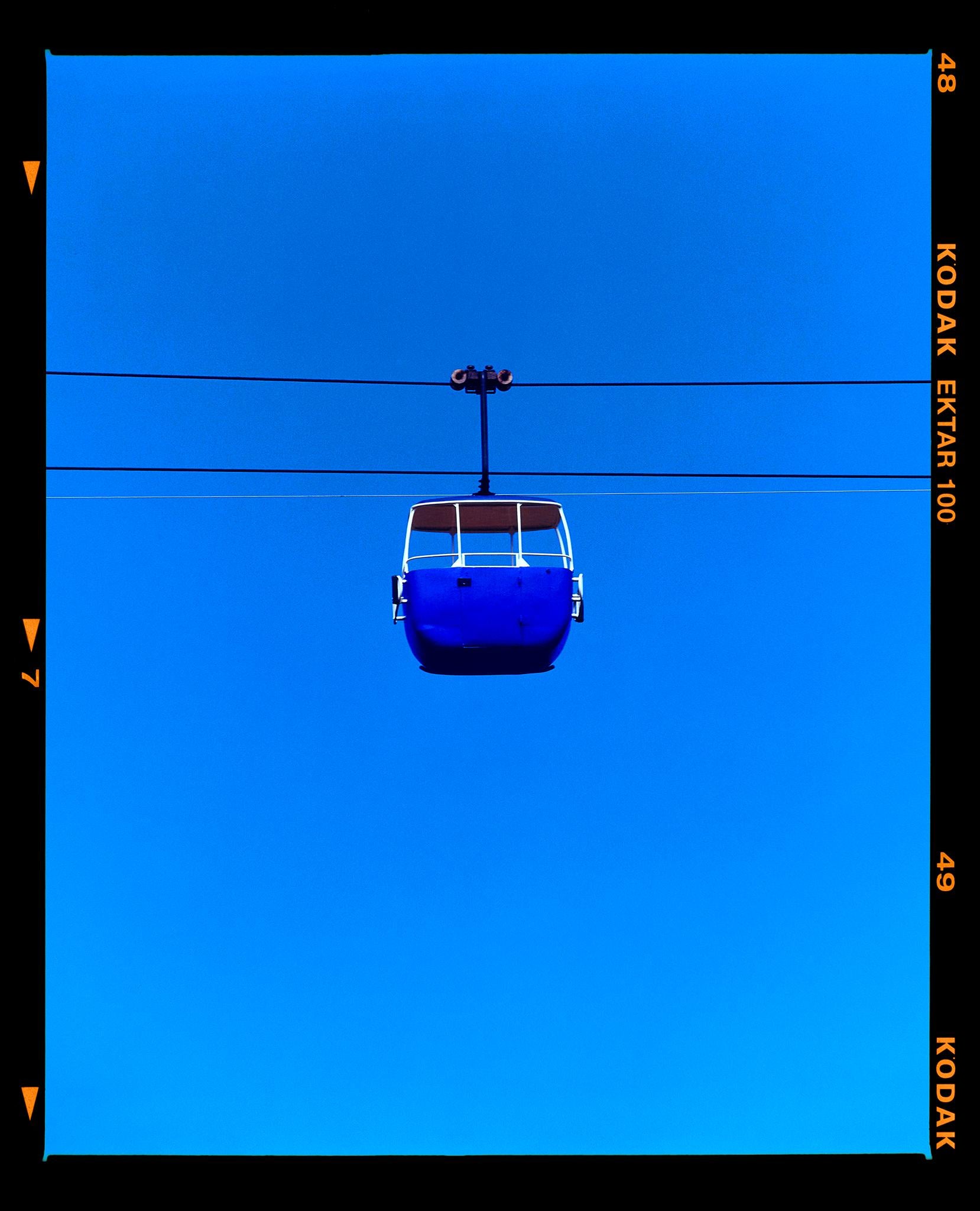 Summit Cable Car (Blue), photograph from Richard Heeps' On-Sea series.

This artwork is a limited edition of 25, gloss photographic print, dry-mounted to aluminium, it is presented in a museum board white window mount and a choice of black or white