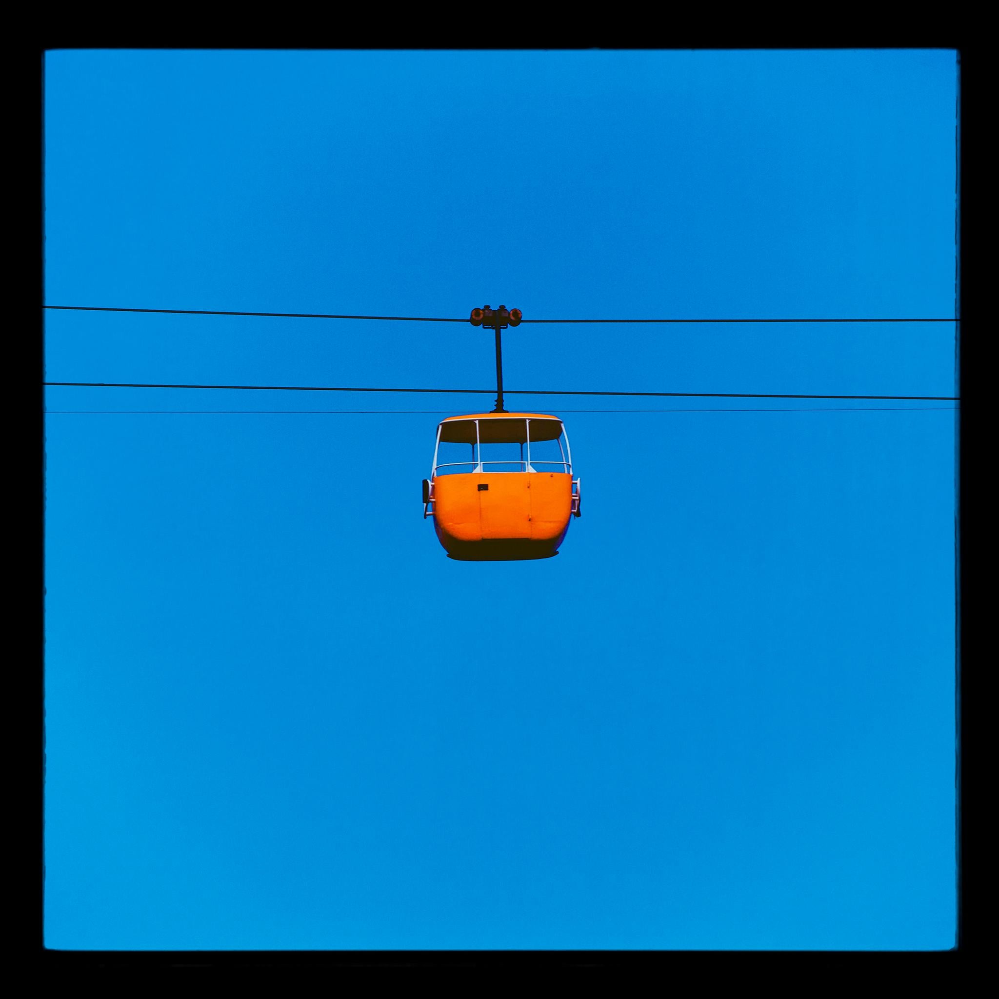 Richard Heeps Color Photograph – Seilbahn „Summit Cable Car Orange“, Llandudno – Farbfotografie-Druck im „Blue Sky Minimalism“-Stil