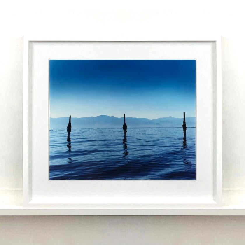 Drei gerahmte Salton Sea-Fotografien. 
Eine Sammlung von blau gefärbten Landschaften und Wasserlandschaften von Richard Heeps Reisen, amerikanischen Roadtrips und Aufnahmen seiner Serie Salton Sea. Die Filme wurden in seiner Dunkelkammer in