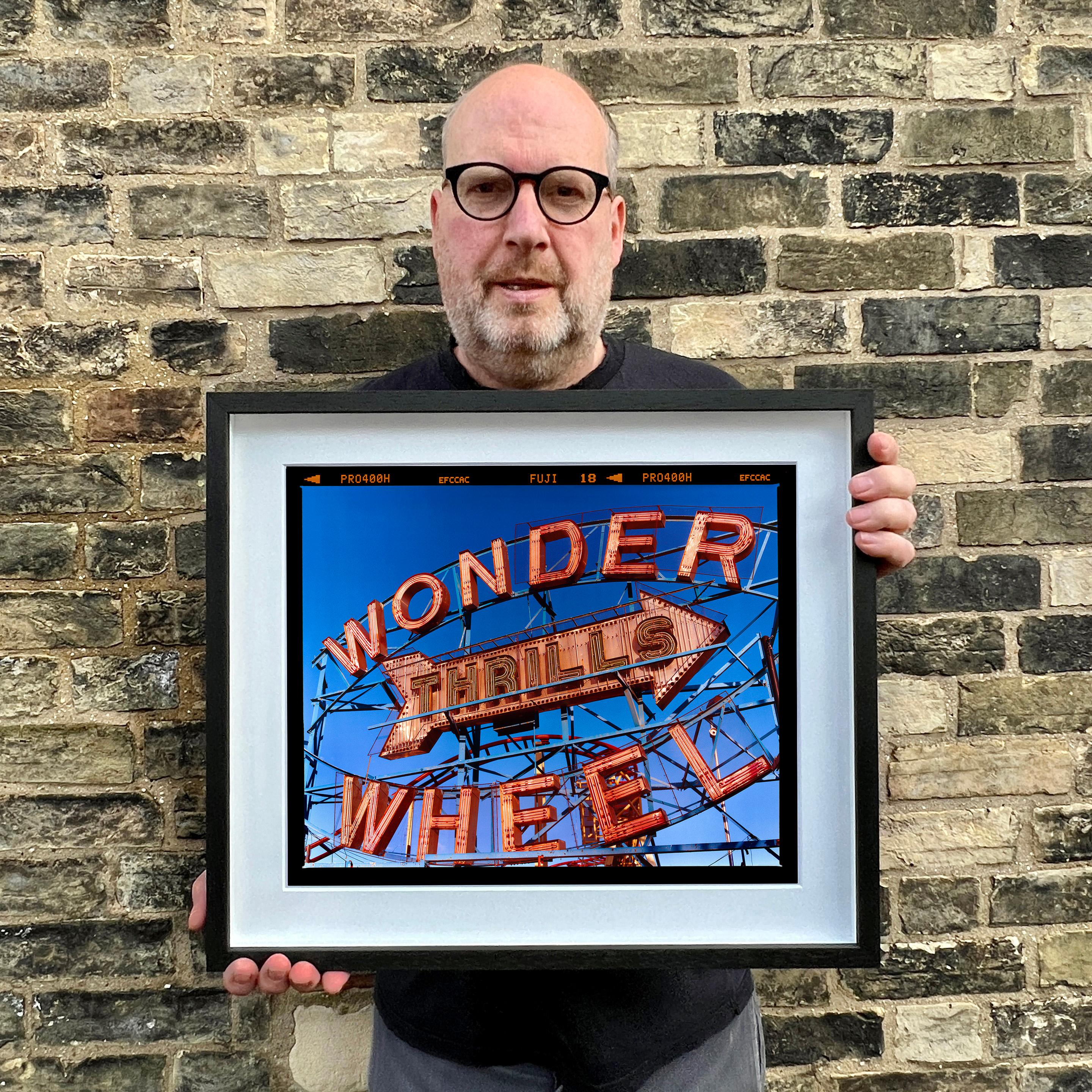 Thrills, das kultige Coney Island Wonder Wheel, fotografiert von Richard Heeps. Die kühne Typografie der architektonischen Struktur füllt den Fuji-Film-Rahmen und kombiniert Richards charakteristische satte blaue und rote Farben.

Dieses Kunstwerk