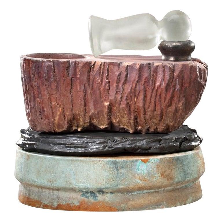 Contemporary American ceramic artist Richard Hirsch's Mortar and Glass Pestle Sculpture was assembled in 2009. It's wheel thrown and hand built clay with red and black glazes, raku patinas and a hot blown glass pestle. The following is an excerpt