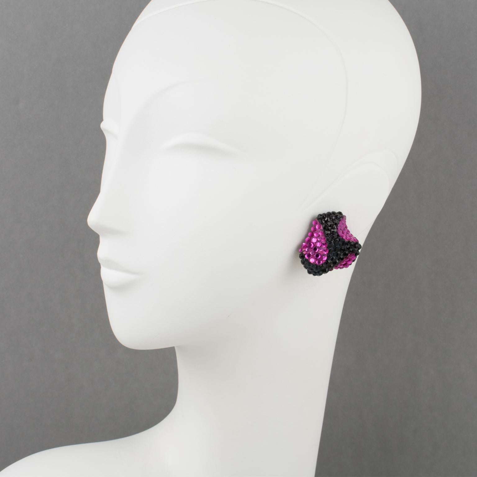 Richard Kerr designed these stunning statement clip-on earrings in the 1980s. They are made of his signature pave rhinestones and feature a dimensional triskelion shape covered with colorful crystal rhinestones on a black resin background framing.