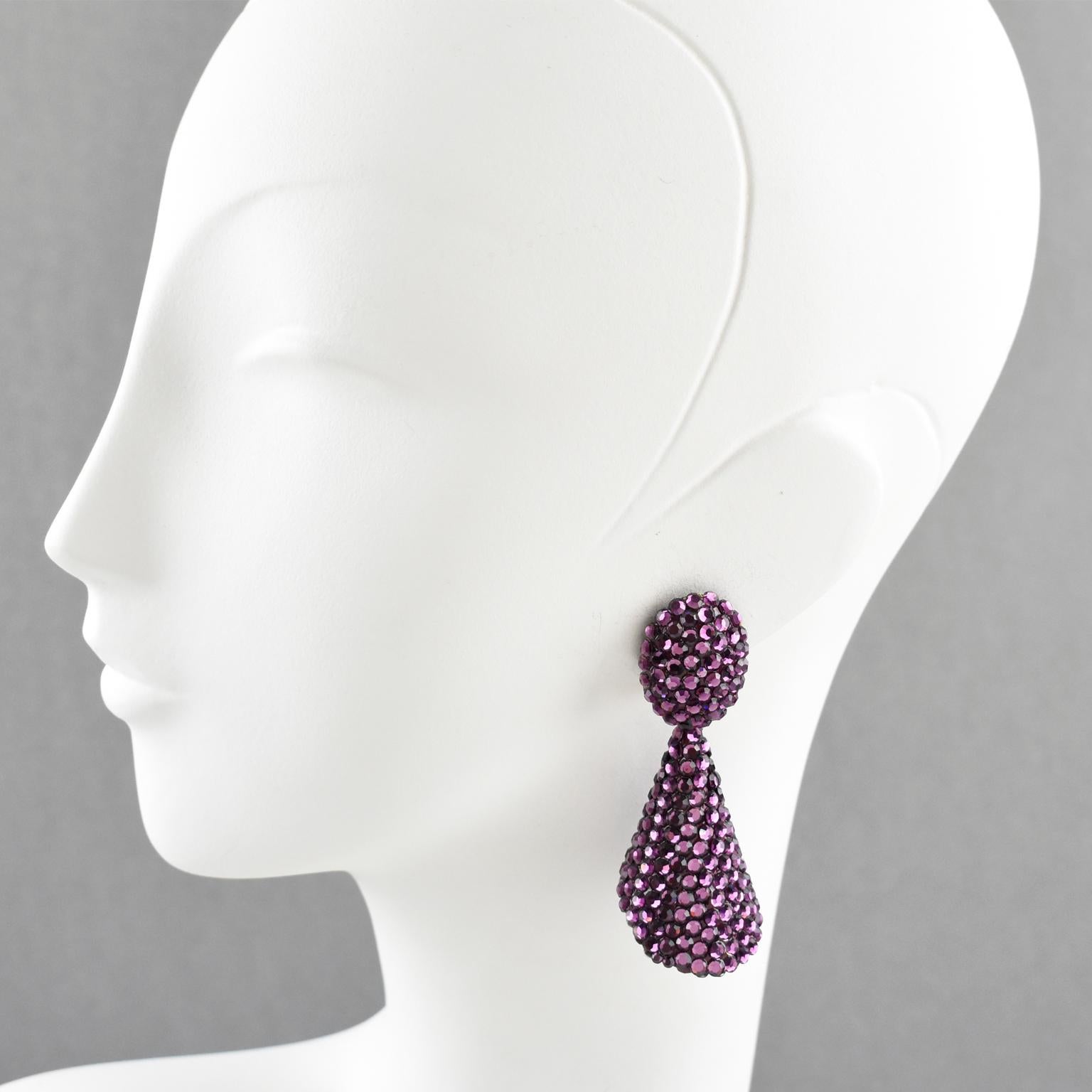 Gorgeous statement clip-on earrings designed by Richard Kerr in the 1980s. They are made up of his signature pave rhinestones. Featuring dangling cone shape all covered with colorful crystal rhinestones on purple resin background frame. Vivid