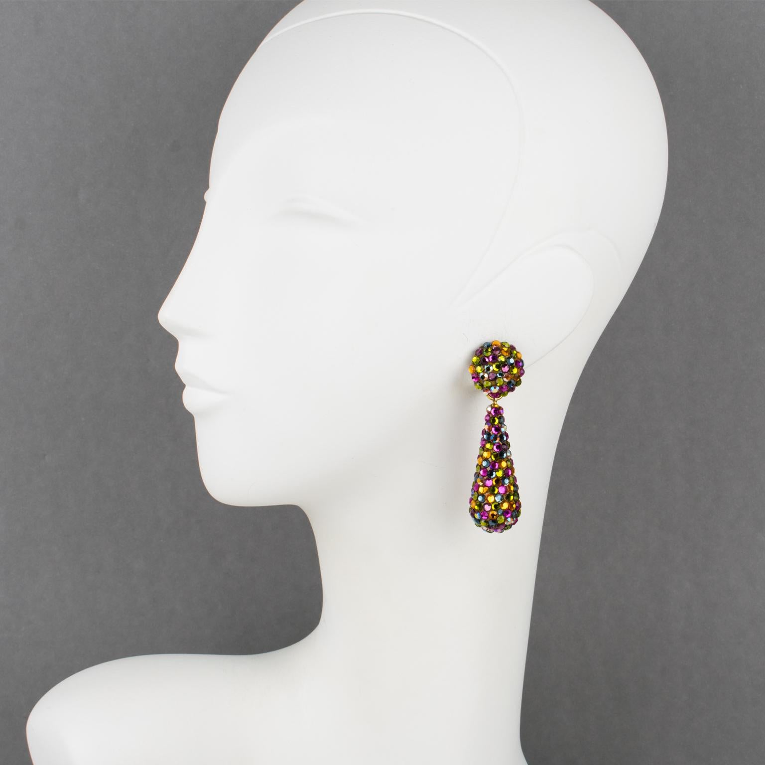 Gorgeous statement clip-on earrings designed by Richard Kerr in the 1980s. They are made of his signature pave rhinestones. 
They feature dangling long teardrop shapes covered with colorful crystal rhinestones on a beige resin background frame.