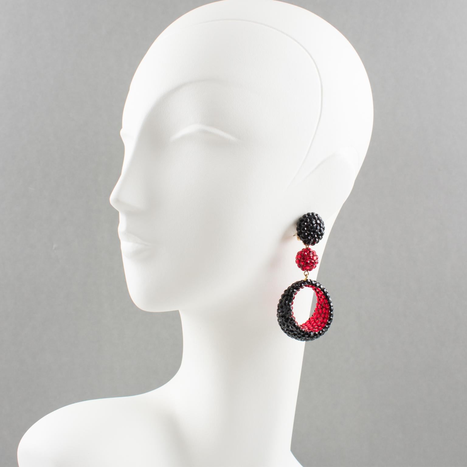 These fancy clip-on earrings were designed by Richard Kerr in the 1980s. They are made up of his signature pave rhinestones. Features oversized dangle shape with bead and asymmetric dimensional donut all covered with red and black crystal