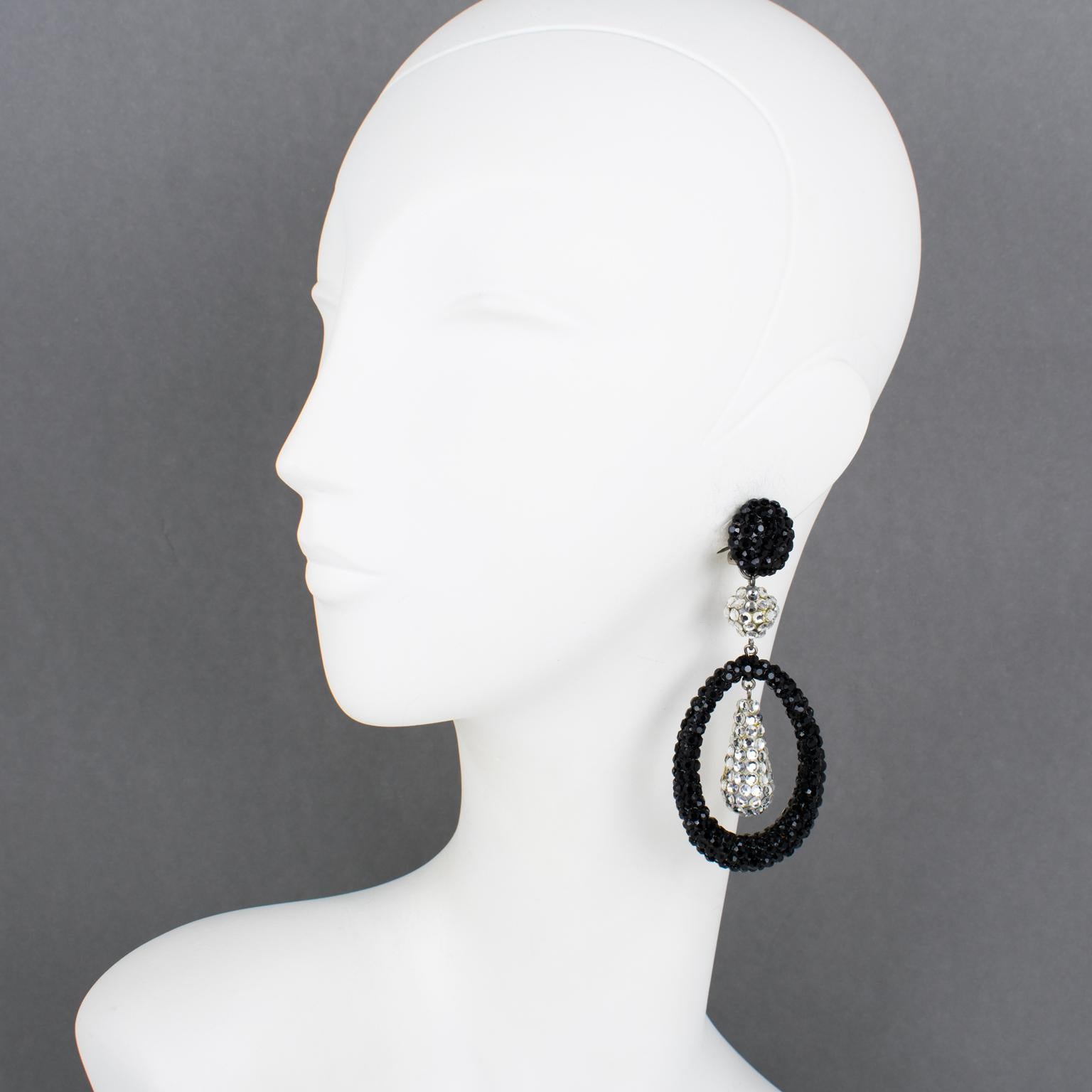 Richard Kerr designed these fabulous statement clip-on earrings in the 1980s. They are composed of his emblematic pavé rhinestones and feature dangling geometric shapes, oval donuts, and teardrops, all covered with silver and black crystal