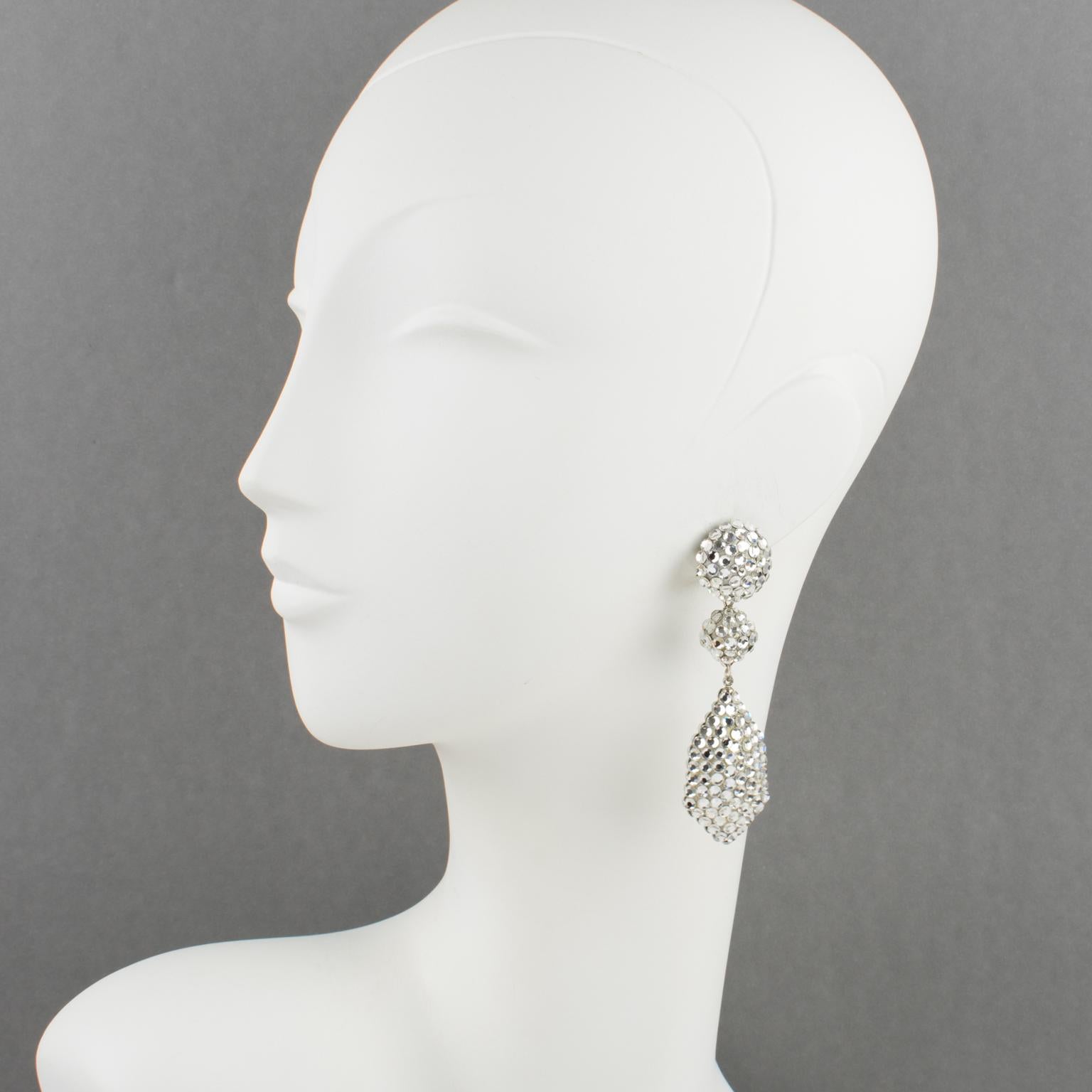 Richard Kerr designed these gorgeous statement clip-on earrings in the 1980s. They are composed of his emblematic pavé rhinestones and feature dangling geometric shapes, all covered with silver crystal rhinestones on a cream-custard resin background