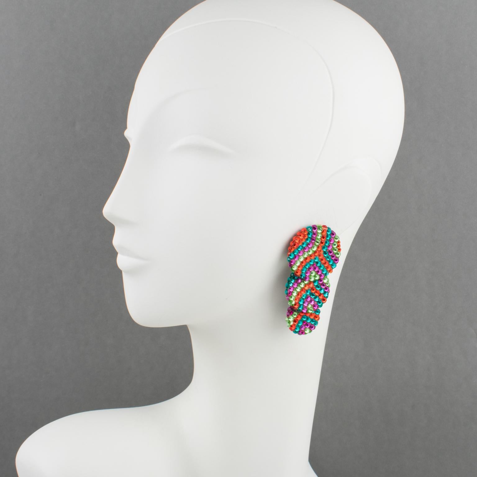 These lovely statements clip-on earrings were designed by Richard Kerr in the 1980s. They are made up of his signature pave rhinestones and feature cascading graduated disk shapes, all covered with colorful crystal rhinestones on a black resin