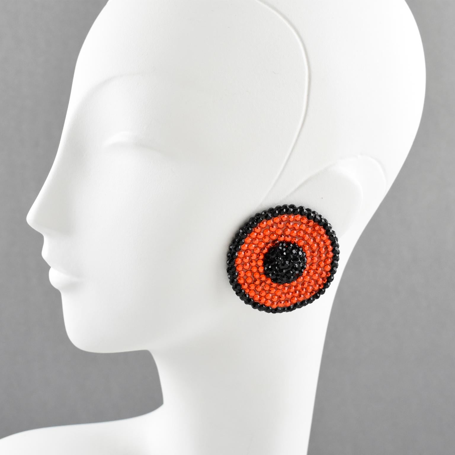 These impressive statement clip-on earrings, designed by Richard Kerr in the 1980s, comprise his signature pave rhinestone design. The pieces boast a large dimensional flat shape with a domed center, all covered with colorful crystal rhinestones in
